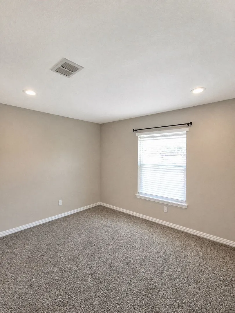 Recessed lighting, neutral wall tones, window with horizontal blinds, black curtain rod, and carpet flooring