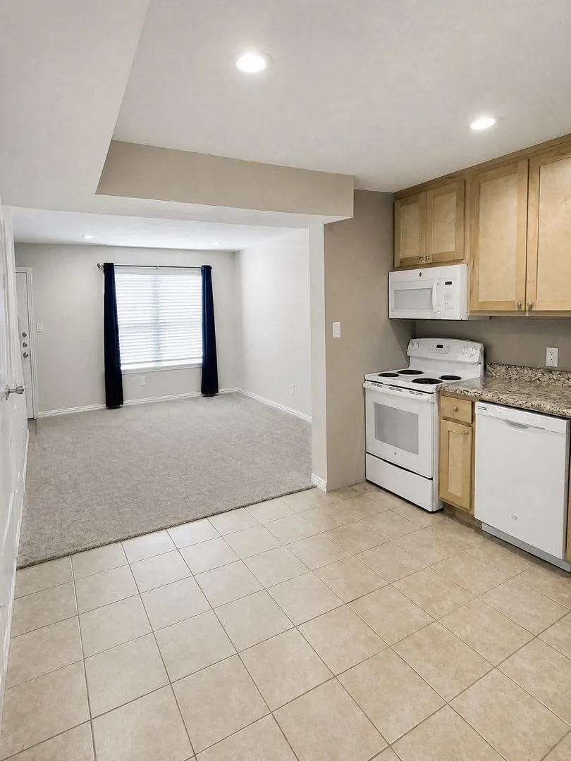 Kitchen featuring tile flooring, wood-finish cabinetry, a white electric range, and a white dishwasher