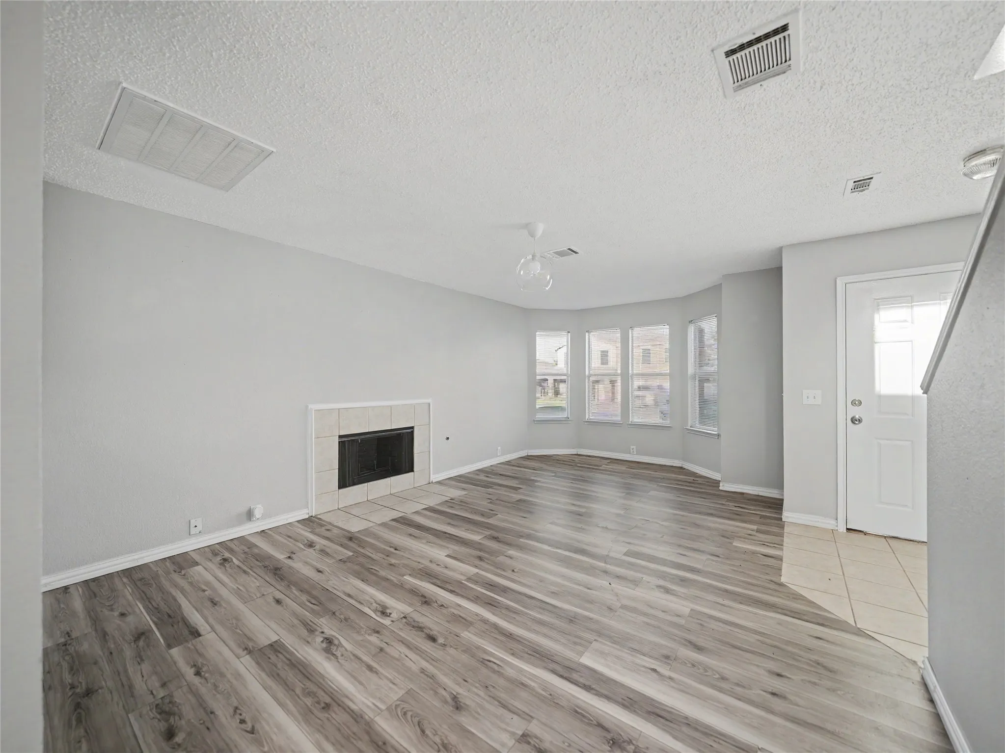 Living area featuring wood-finish flooring, a tiled fireplace, and a bay window