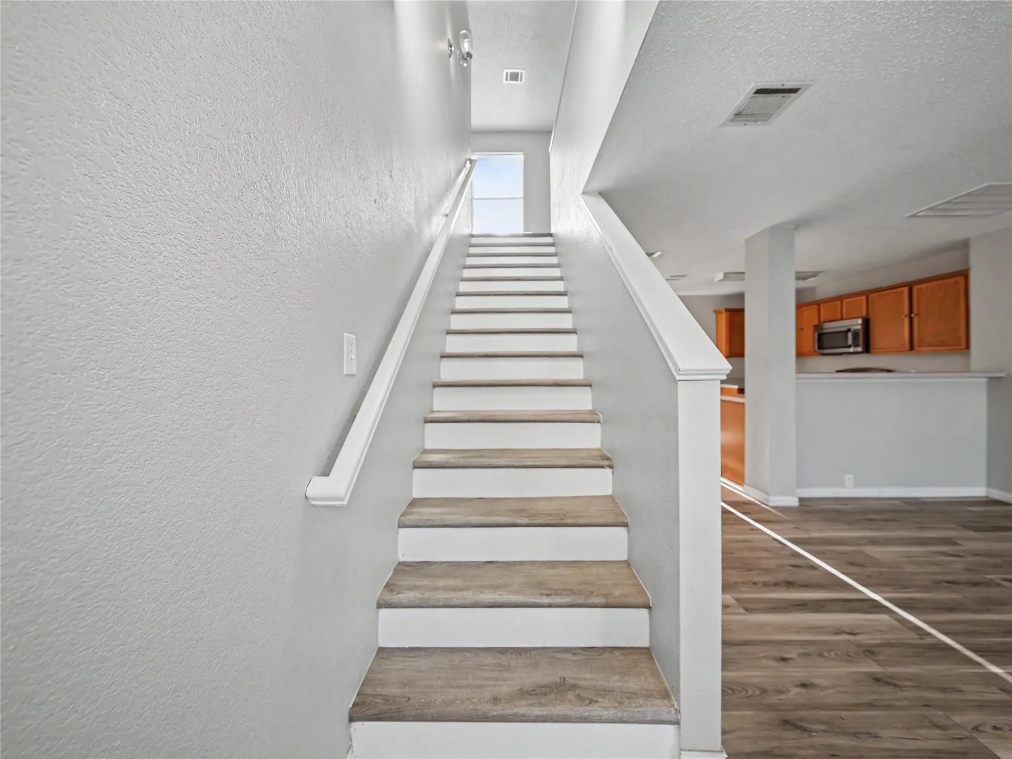 Staircase with wood-finish treads and white risers, featuring a white handrail
