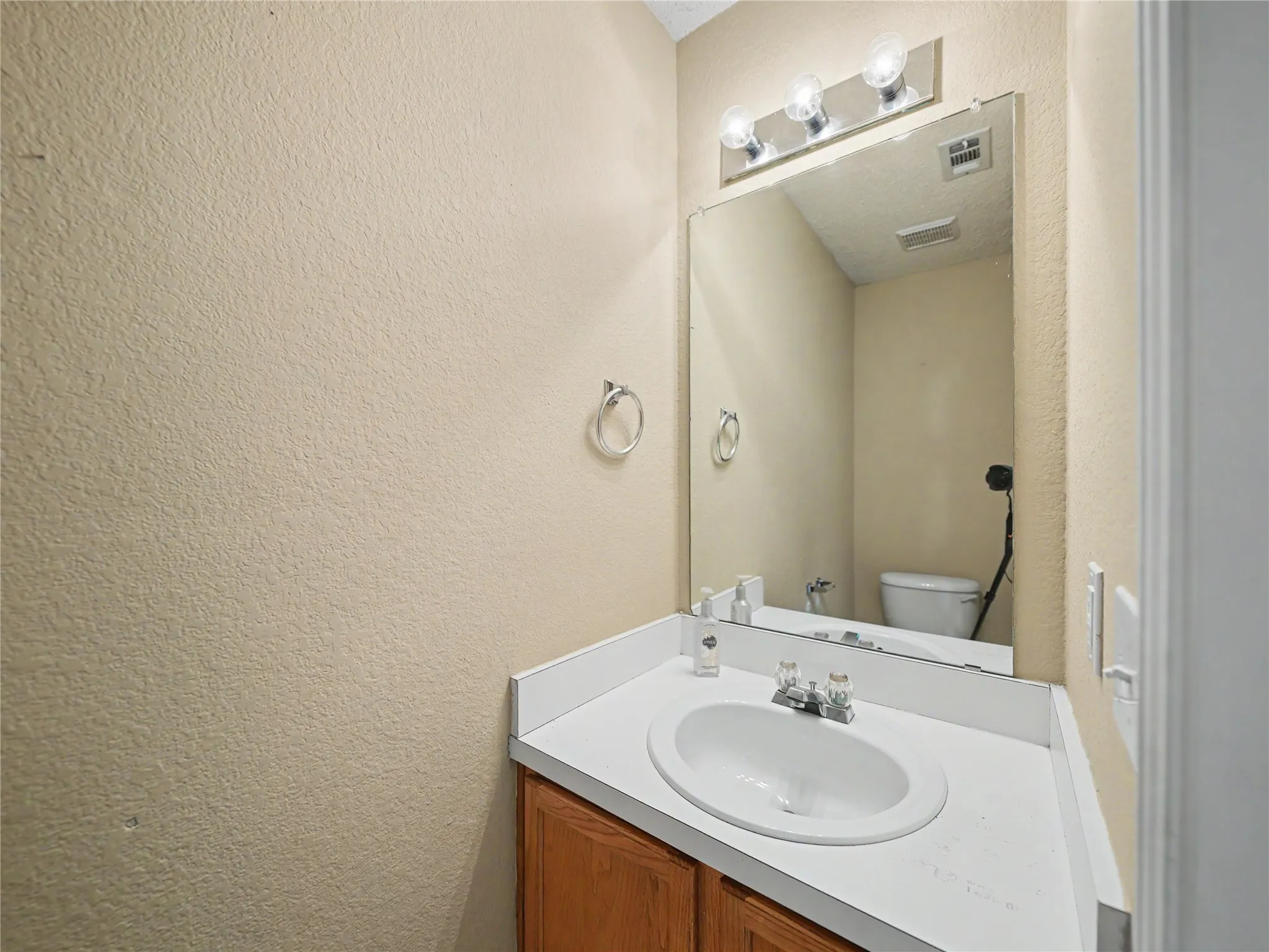 Vanity with laminate countertop, integrated sink, and wood-finish cabinetry