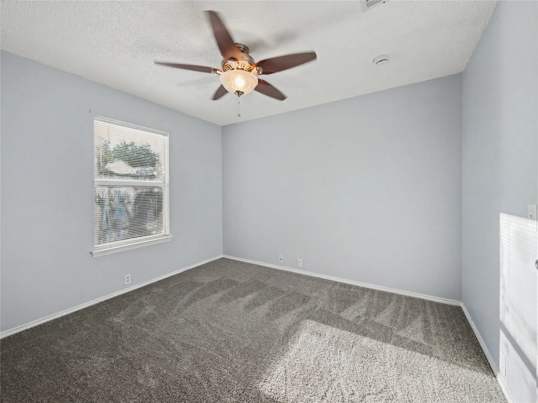 Carpeted flooring, a window with blinds, and a ceiling fan with integrated lighting