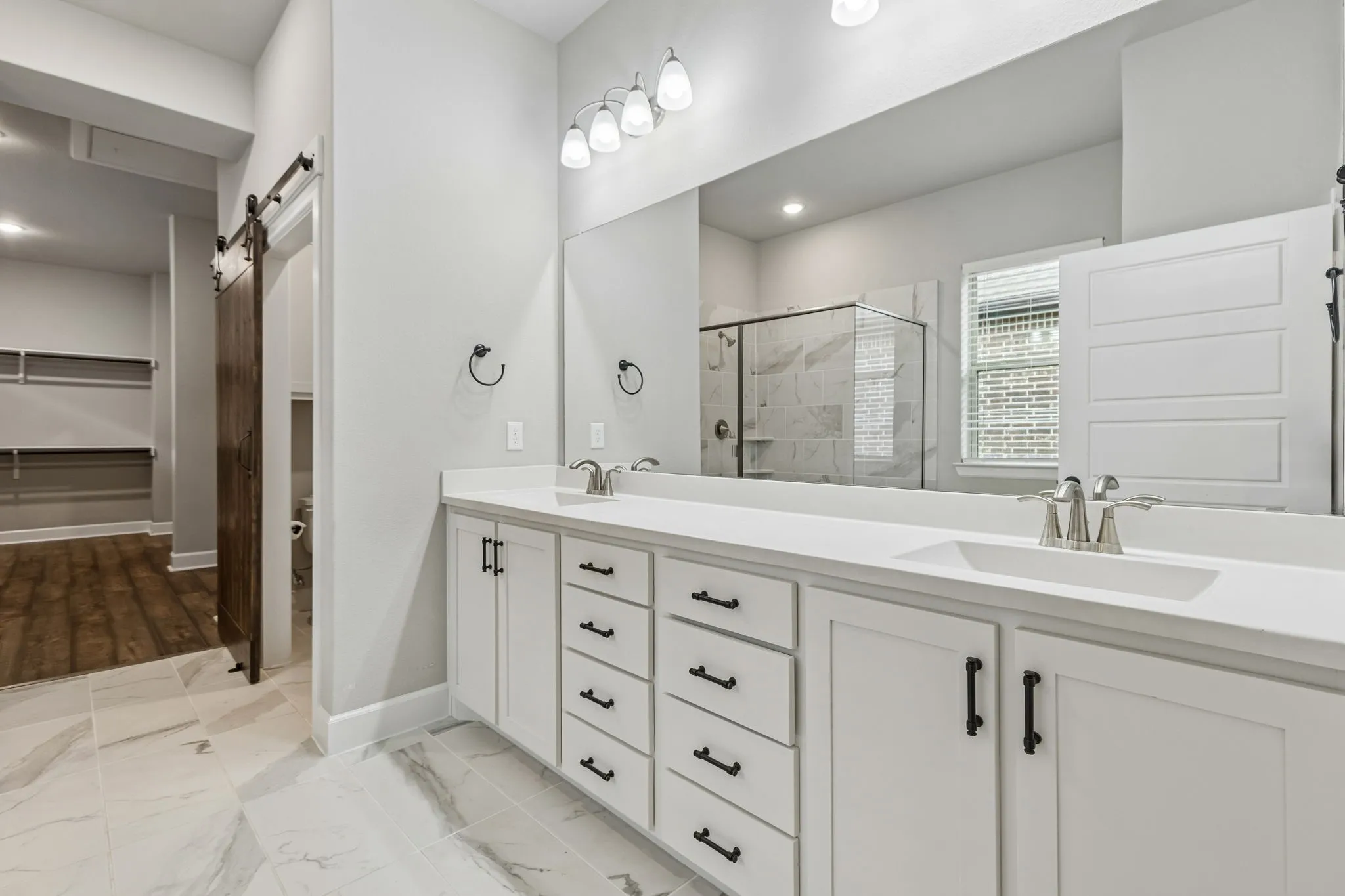 Dual vanity with white cabinetry, matte black hardware, and a large mirror
