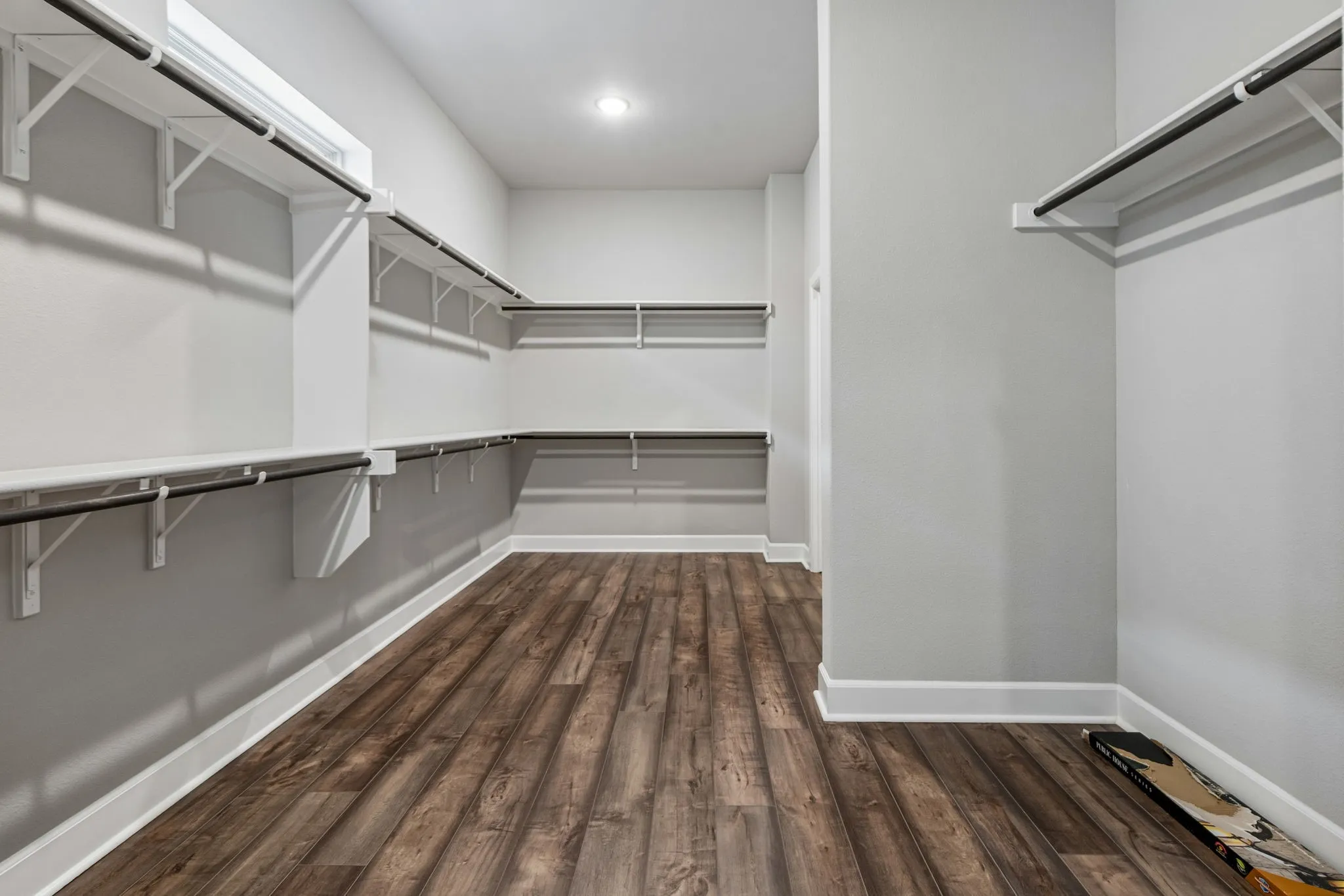 Walk-in closet featuring wood-finish flooring, recessed lighting, and extensive built-in shelving with hanging rods