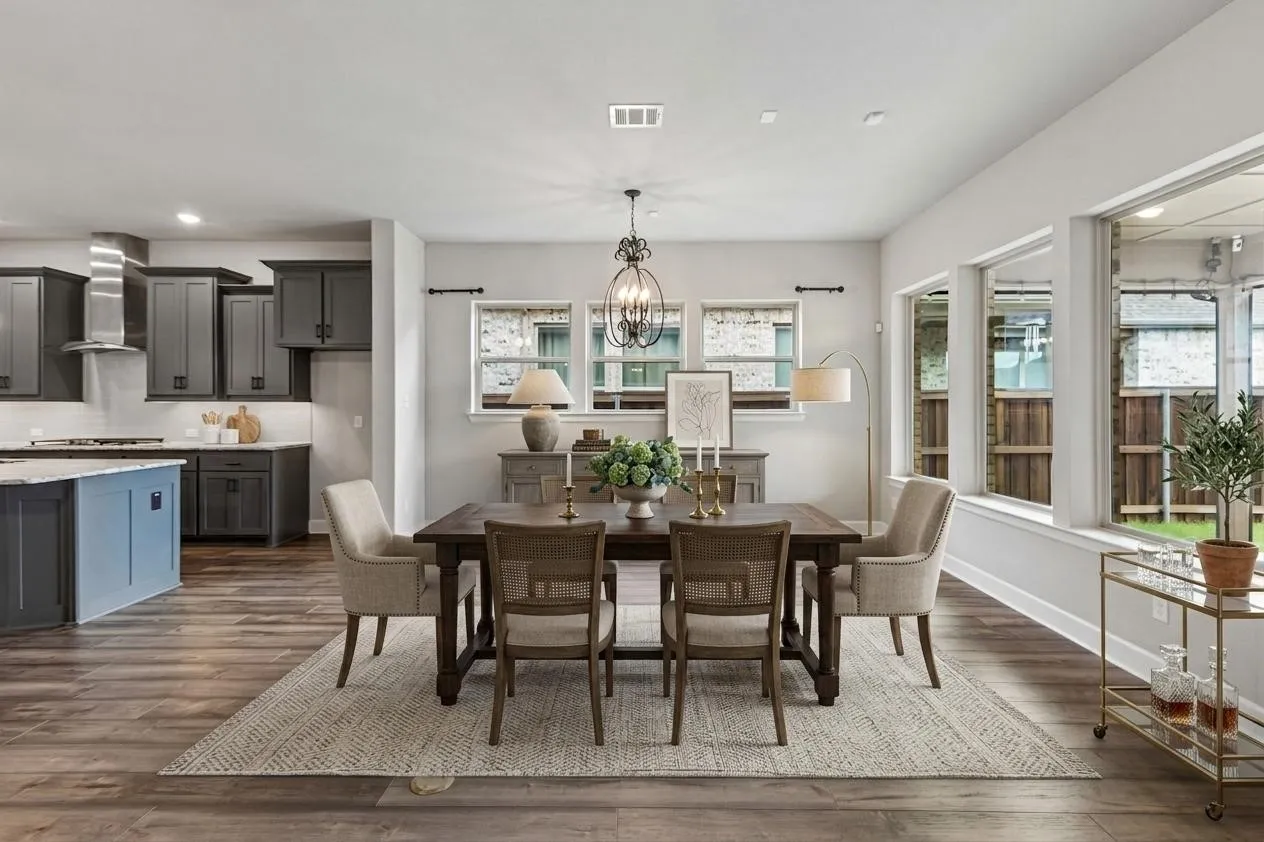 Open-concept dining area featuring wood-finish flooring, a decorative chandelier, and a wide window opening to the outdoor space