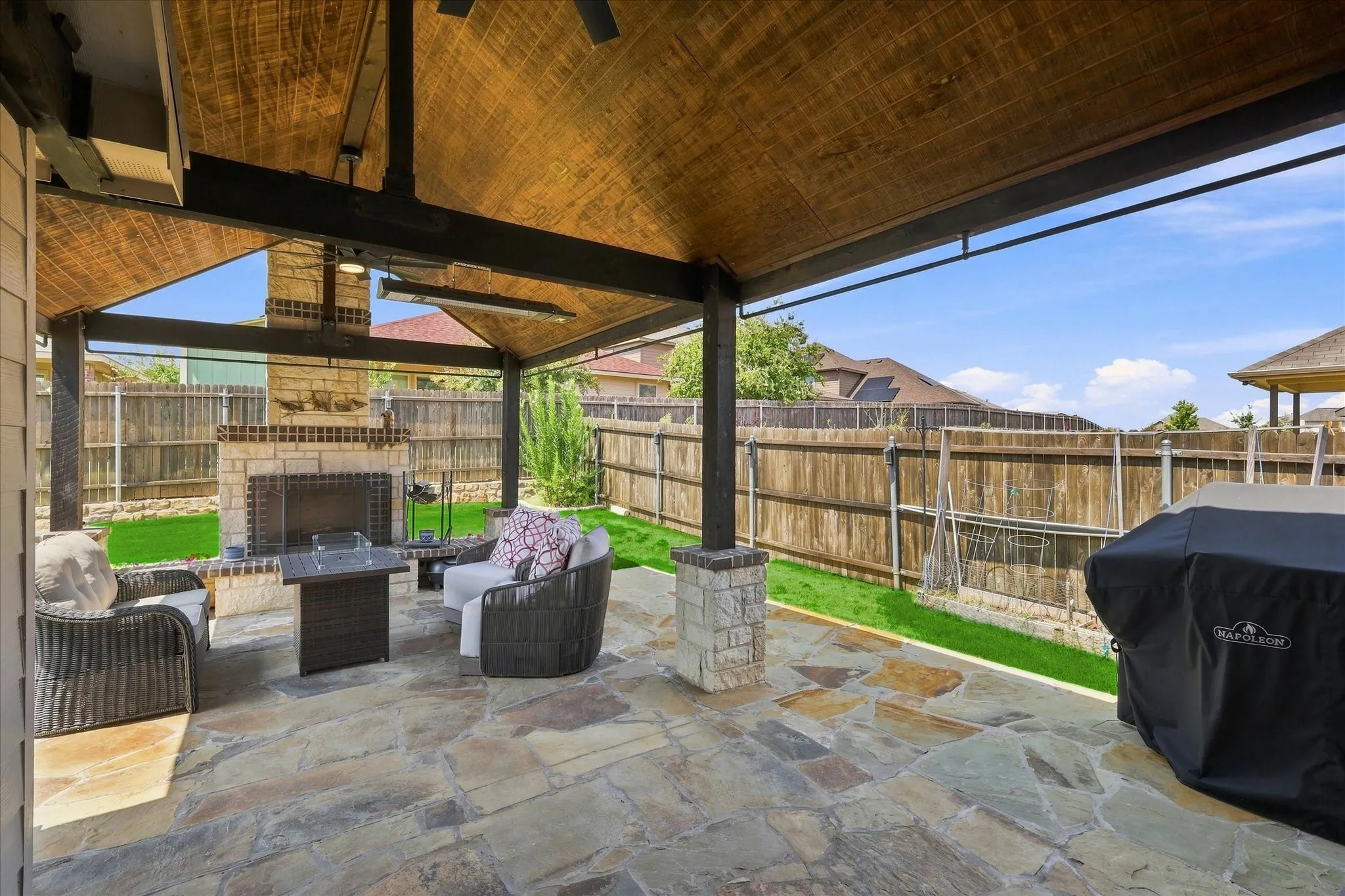 Impressive Outdoor Living Area features an Expansive Covered Flagstone Patio, Wood-plank Vaulted Ceiling, Exposed Beams, Lighted Ceiling Fan, Outdoor Heater. A Dramatic Floor-to-Ceiling Stone Wood Burning Fireplace Anchors the Space, while the Extended Patio and Large Fenced Backyard provide Plenty of Room for Dining, Grilling and Entertaining.
