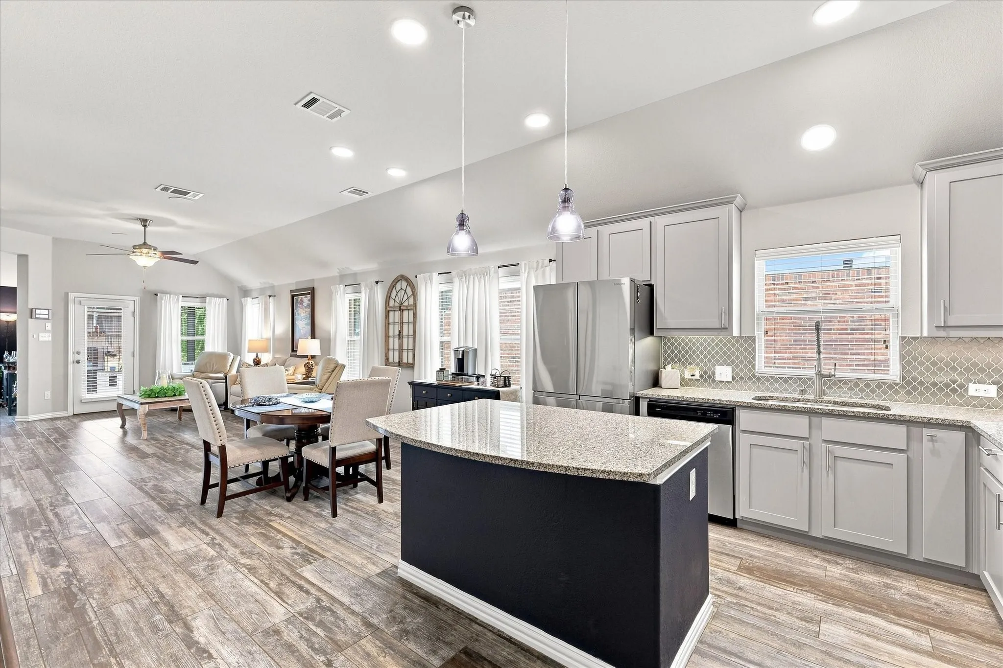 Cook’s Kitchen Open to Living Areas features A Large Center Island Provides Generous Prep and Serving Space, Breakfast Bar Seating, and Stylish Pendant Lighting
