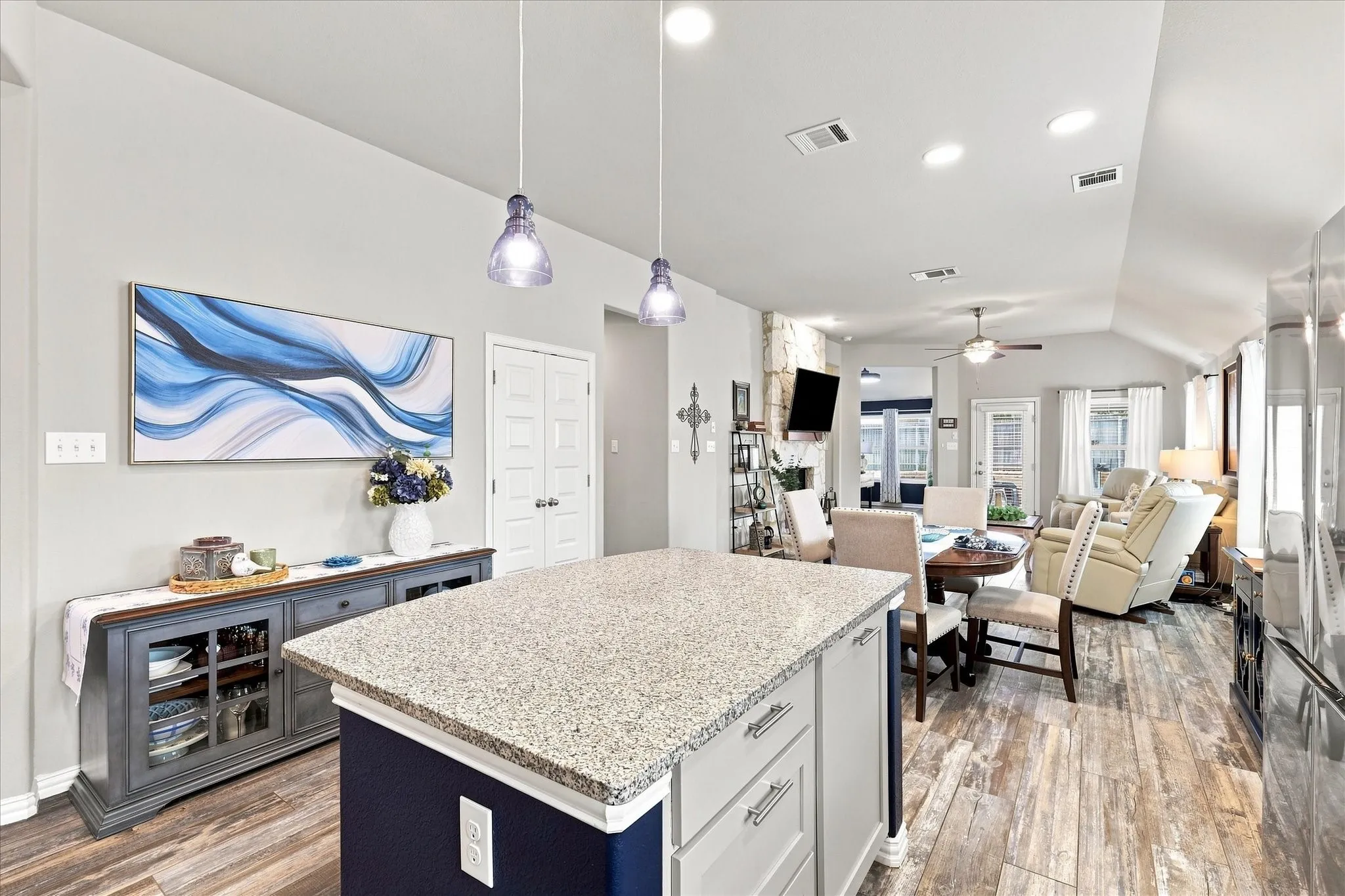 Cook’s Kitchen Open to Living Areas features A Large Center Island Provides Generous Prep and Serving Space, Breakfast Bar Seating, and Stylish Pendant Lighting