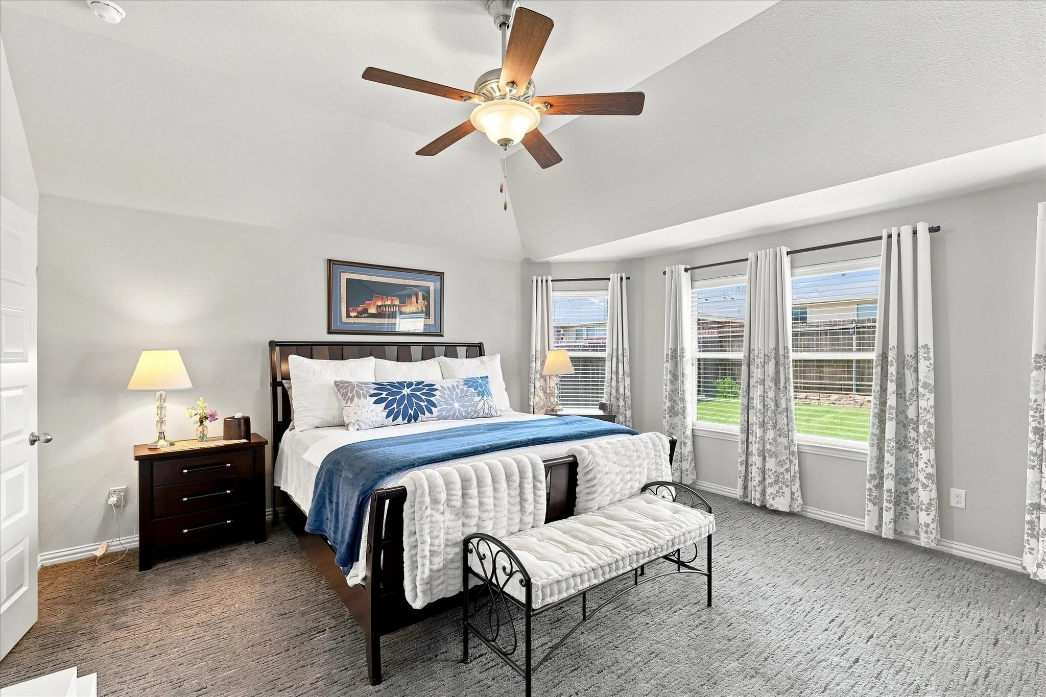 Spacious Primary Suite features a Soaring Vaulted Ceiling, Lighted Ceiling Fan, Plush Carpeting and Abundant Natural Light from multiple windows. Generous proportions provide Room for Additional Furnishings, while Direct Ensuite Bath Access creates a Comfortable Owner’s Retreat.