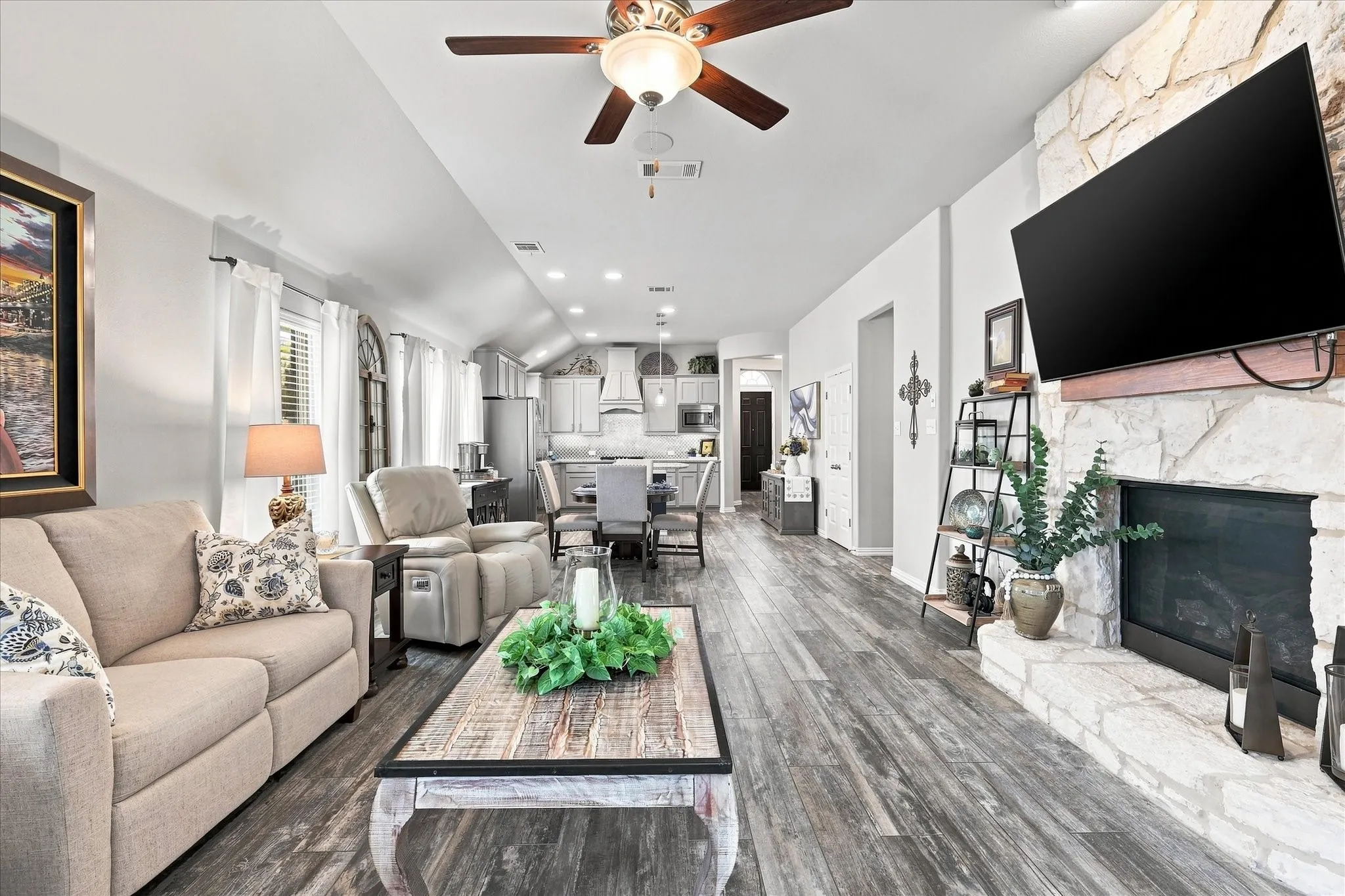 Spacious Living Room with Vaulted Ceiling, Floor-to-Ceiling Natural Stone Gas Fireplace, Wood-look Tile Floors and Abundant Windows. The Open Design flows into the Casual Dining and Kitchen with Easy Access to Large Covered Outdoor Living and Private Fenced Back Yard.