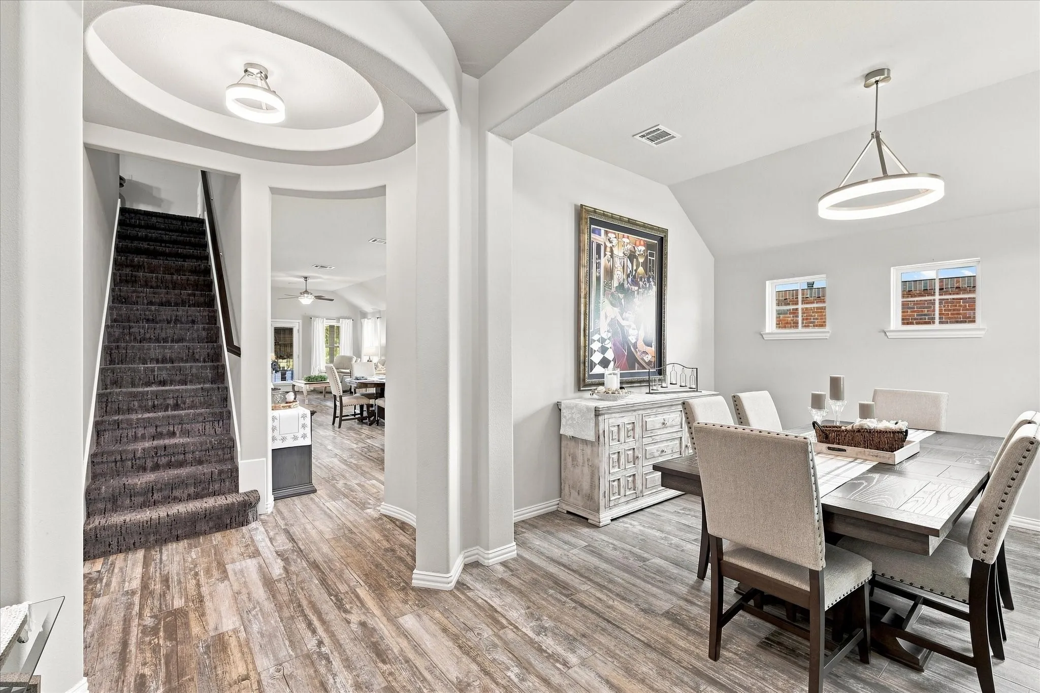 Formal Dining Room features a Vaulted Ceiling, Contemporary Designer Lighting, Upgraded Wood-look Tile Flooring and Abundant Natural Light. The Open Design and Architectural Details create an Impressive Space for Entertaining.