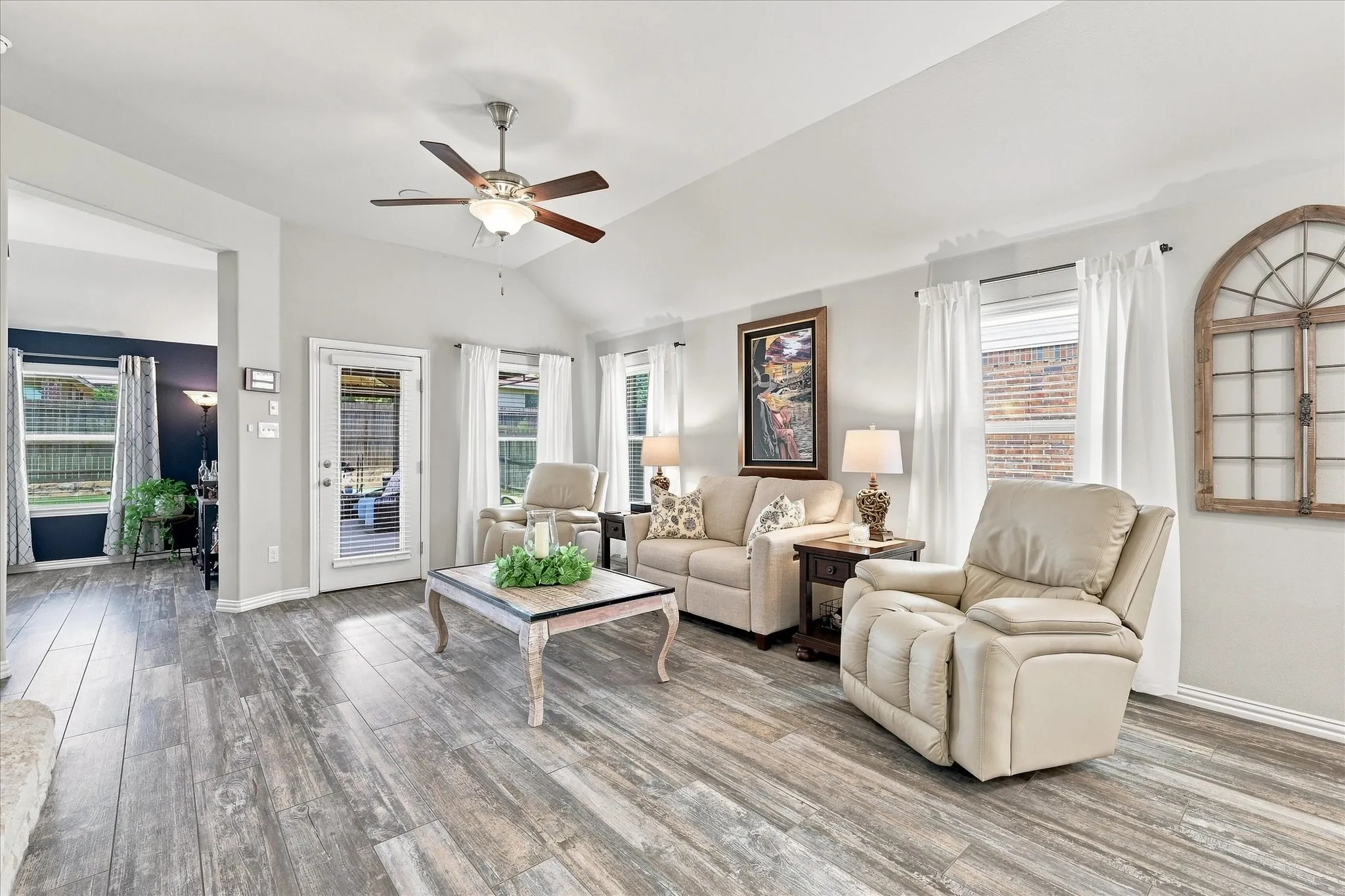 Spacious Living Room with Vaulted Ceiling, Floor-to-Ceiling Natural Stone Gas Fireplace, Wood-look Tile Floors and Abundant Windows. The Open Design flows into the Casual Dining and Kitchen with Easy Access to Large Covered Outdoor Living and Private Fenced Back Yard.