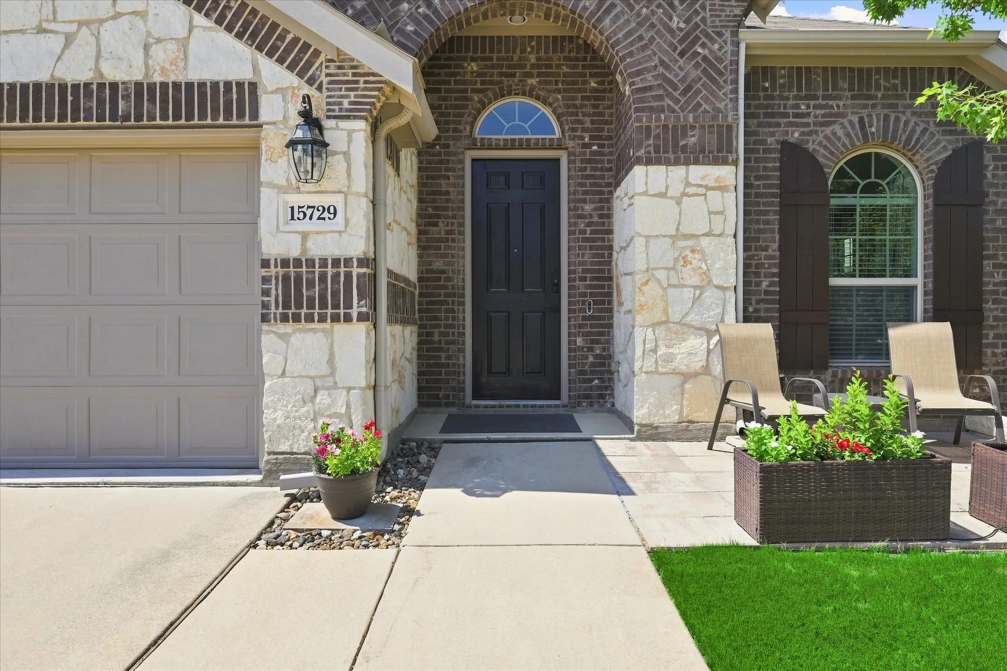 Welcoming Covered Entry featuring Dramatic Arched Brick Detailing, Stone Columns, and a Handsome Front Door.