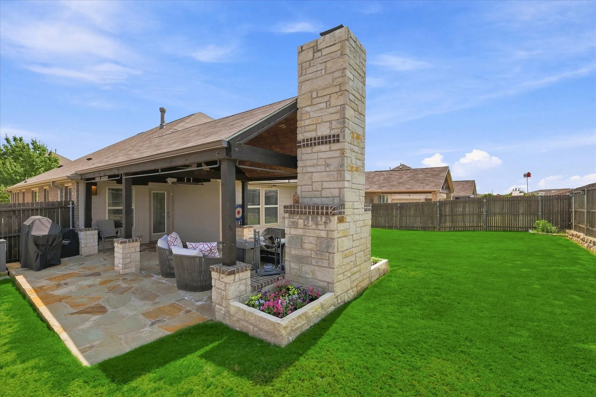 Impressive Outdoor Living Area features an Expansive Covered Flagstone Patio, Wood-plank Vaulted Ceiling, Exposed Beams, Lighted Ceiling Fan, Outdoor Heater. A Dramatic Floor-to-Ceiling Stone Wood Burning Fireplace Anchors the Space, while the Extended Patio and Large Fenced Backyard provide Plenty of Room for Dining, Grilling and Entertaining.