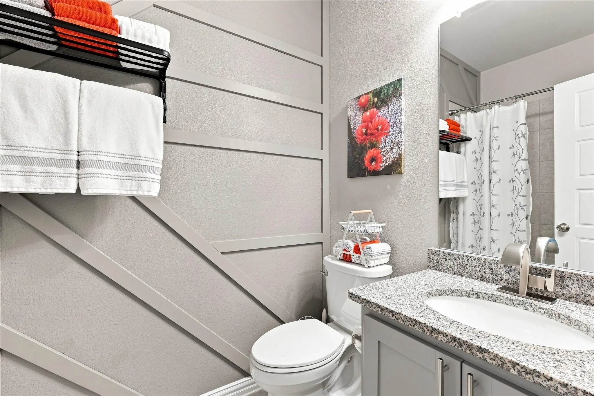 Stylish Main Bath features a Granite-Topped Mirrored Vanity, Updated Cabinetry, and Full Tub with Tile Surround, and A Distinctive Decorative Accent Wall adds Architectural Character and a Custom Touch.