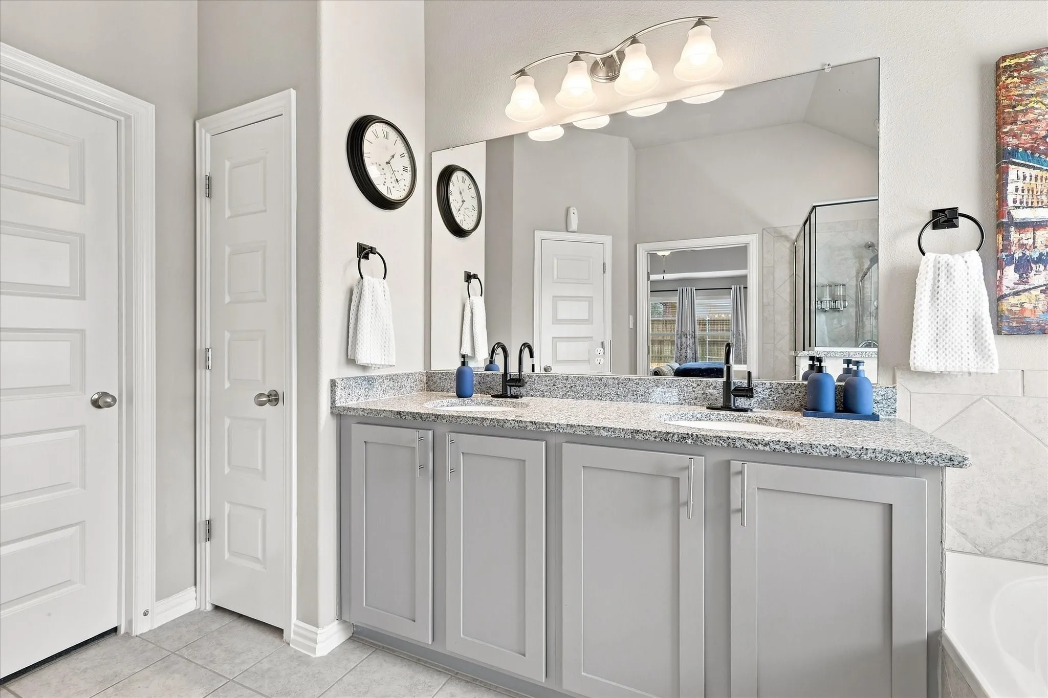 Spacious Primary Bath features a Vaulted Ceiling, Dual-sink Granite Mirrored Vanity, Abundant Cabinetry, Tile Flooring. A Deep Soaking Tub with Tiled Surround Complemented by a Separate Tiled Walk-in Shower with Frameless Glass Enclosure and Built-in Corner Shelves. There's also Convenient Access to the Linen and Walk-in Closets.