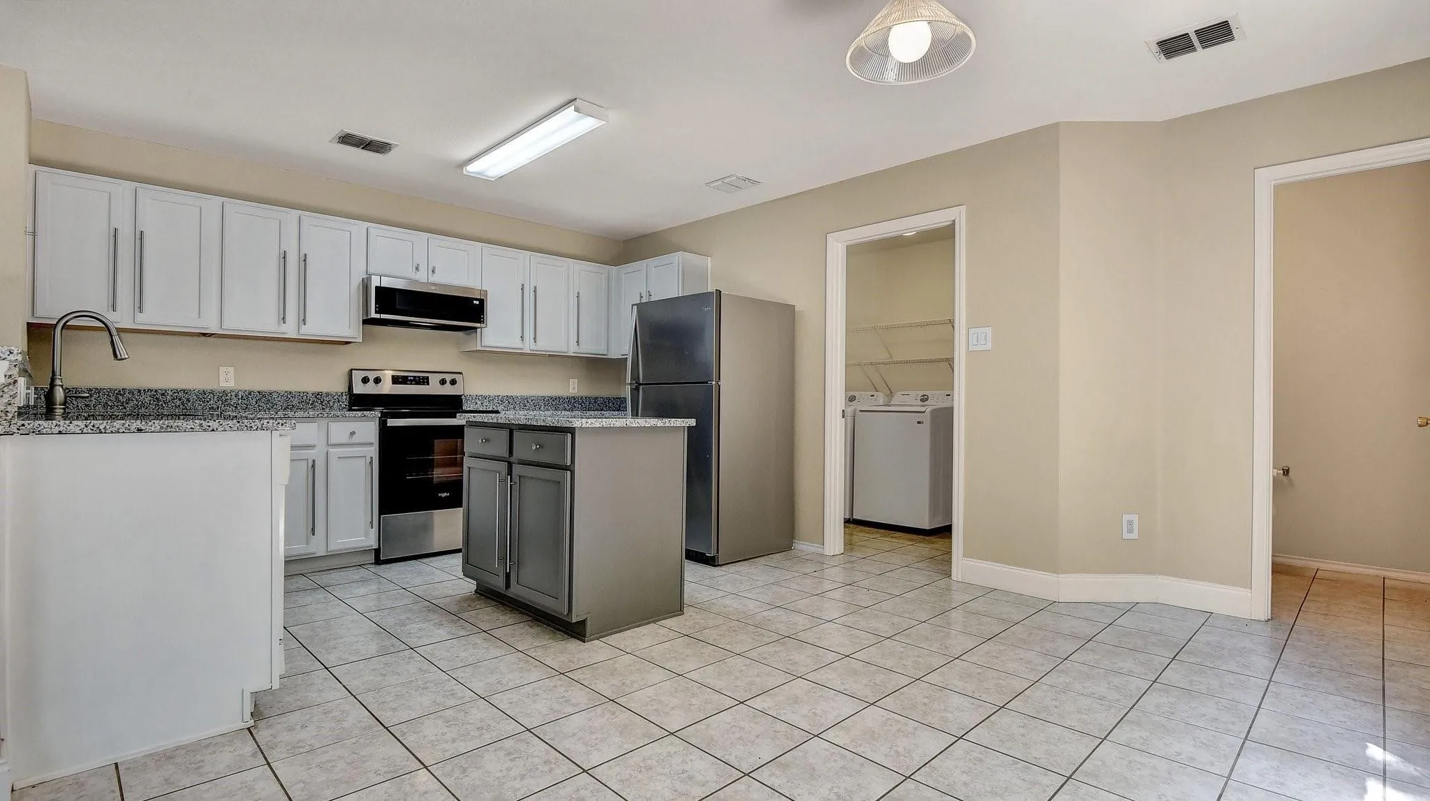 Kitchen featuring white cabinetry, a center island with storage, stainless steel appliances, and tile flooring
