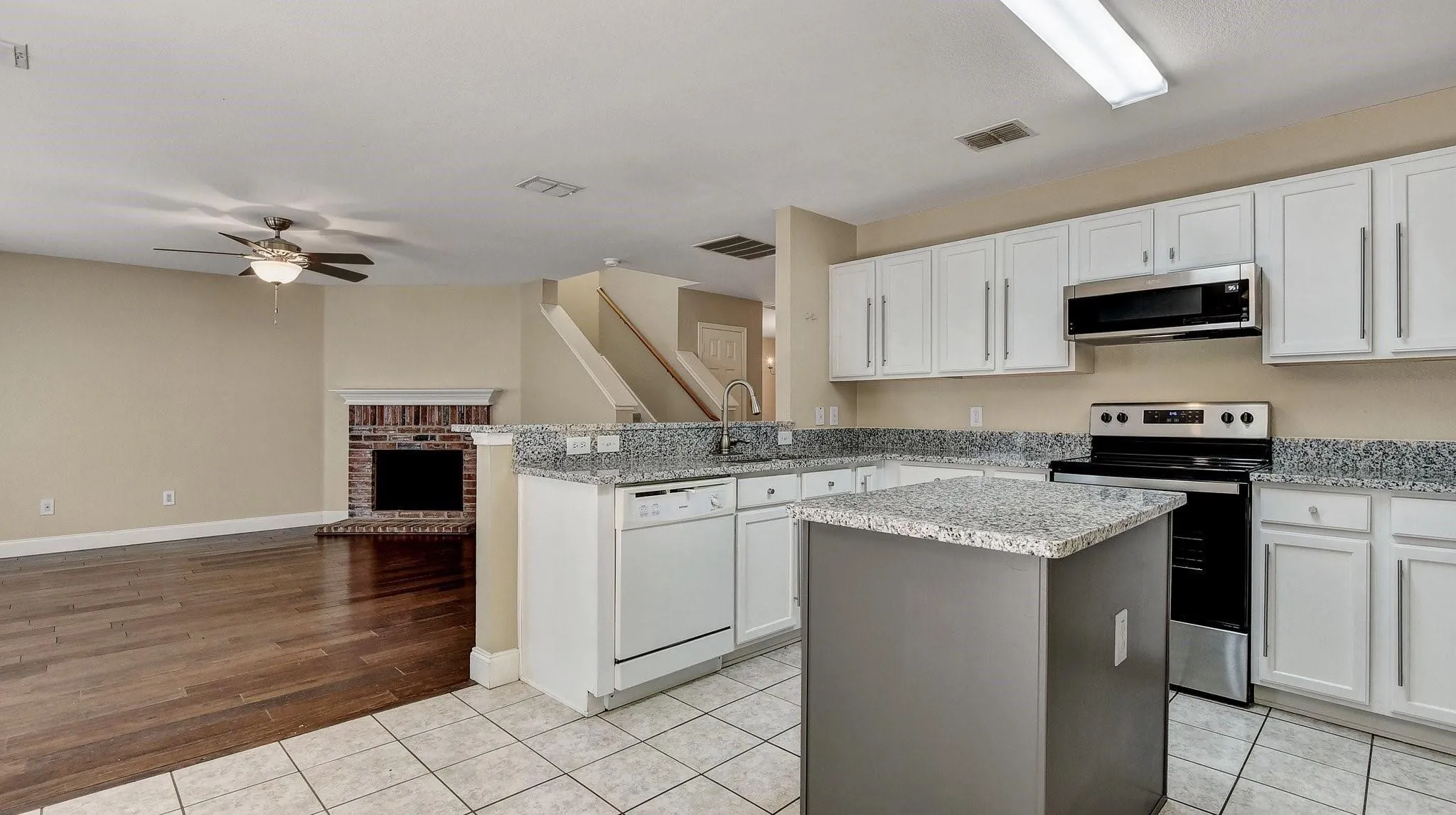 Kitchen with white cabinetry, stainless steel appliances, granite countertops, and a central island