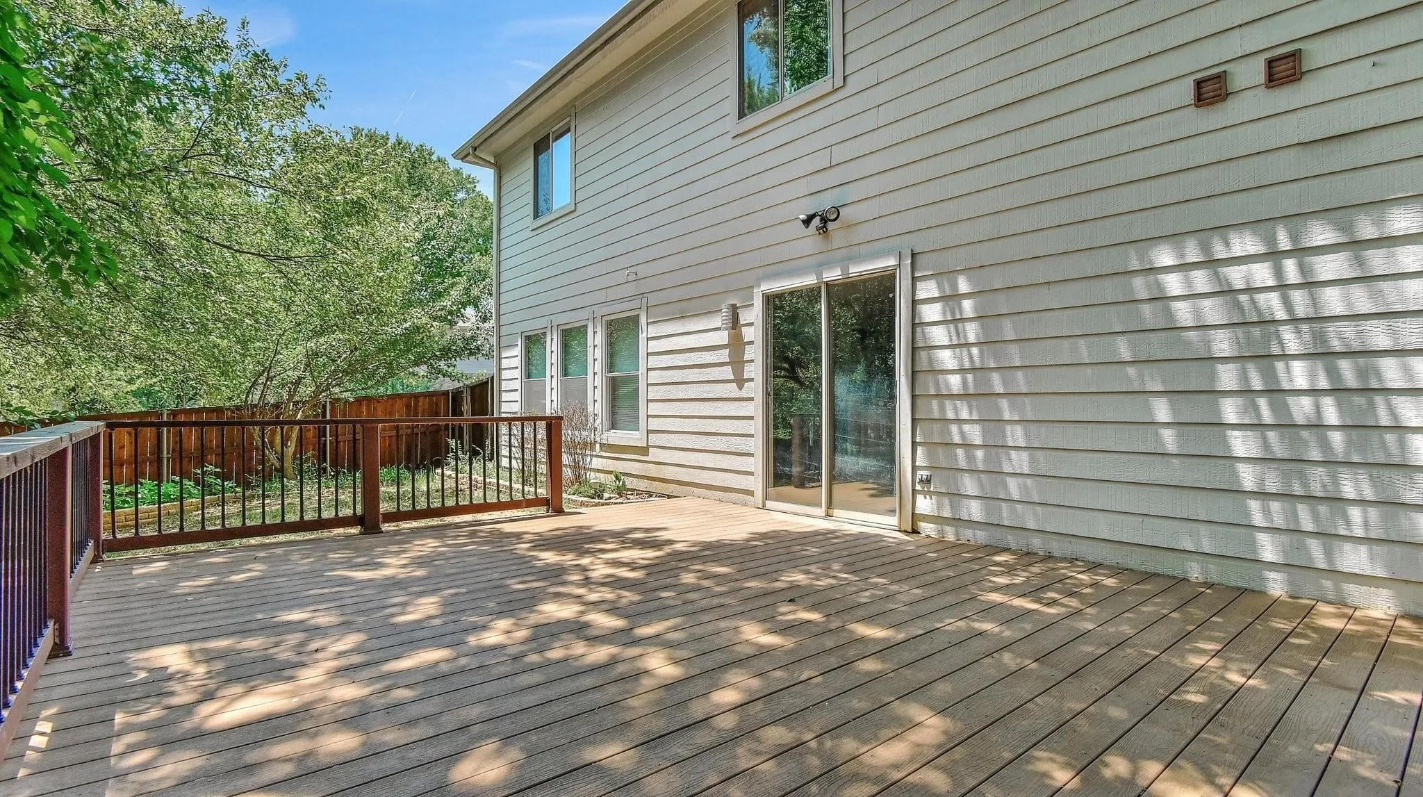 Expansive outdoor deck with wood railing, offering direct access to the interior through a sliding glass door