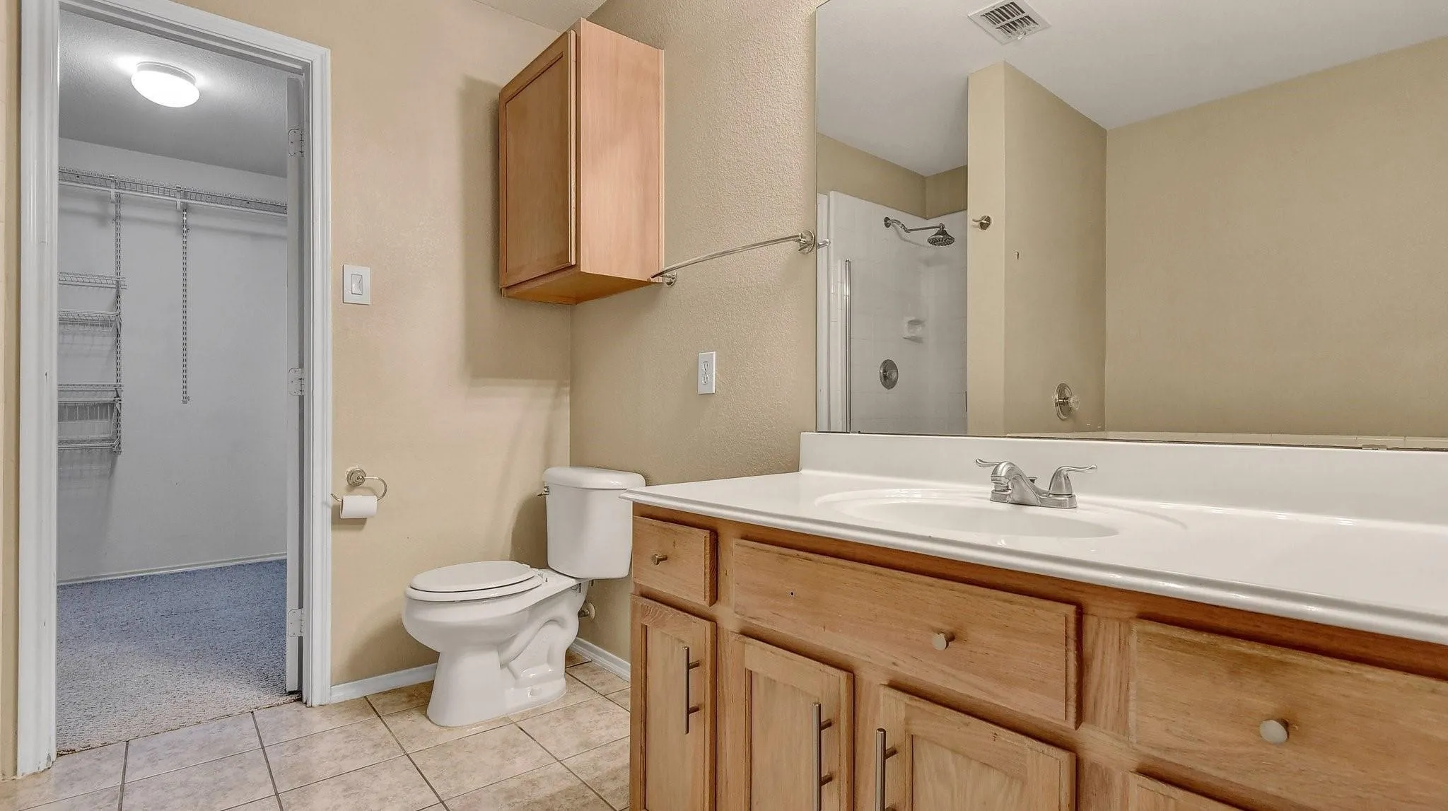 Bathroom featuring a single vanity with wood-finish cabinetry, a drop-in sink, and a framed mirror