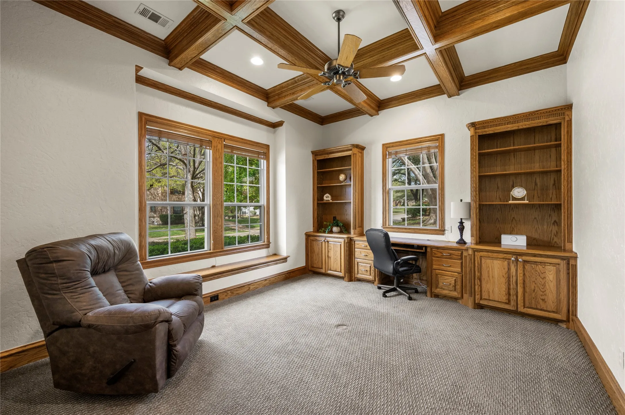 Front study with beamed ceiling and windows that view the front. The golf course can be slightly seen between the houses across the street.