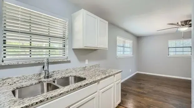 Kitchenette with white cabinetry, granite-style countertops, and a dual basin stainless steel sink