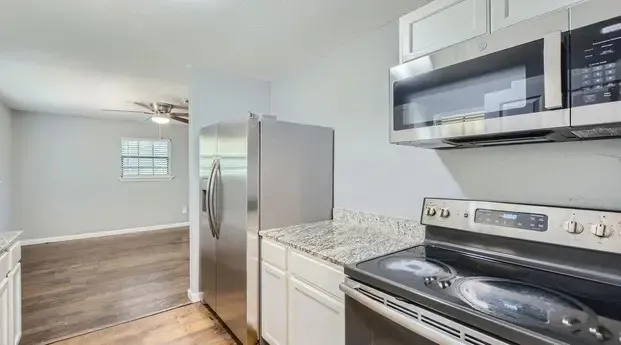 Kitchen featuring stainless steel appliances, white cabinetry, and light-colored countertops