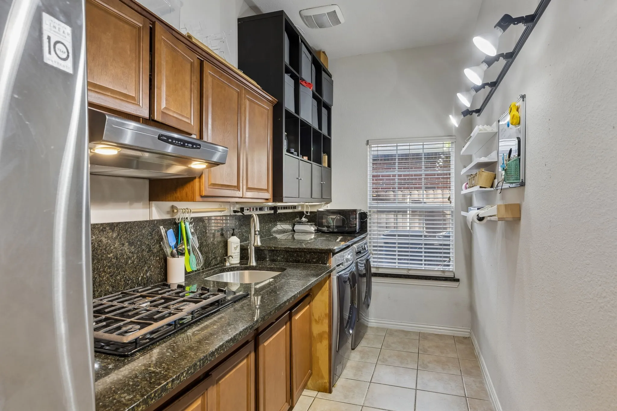Laundry room featuring granite counter tops, sink, cabinets, vent-hood and a gas cooktop.