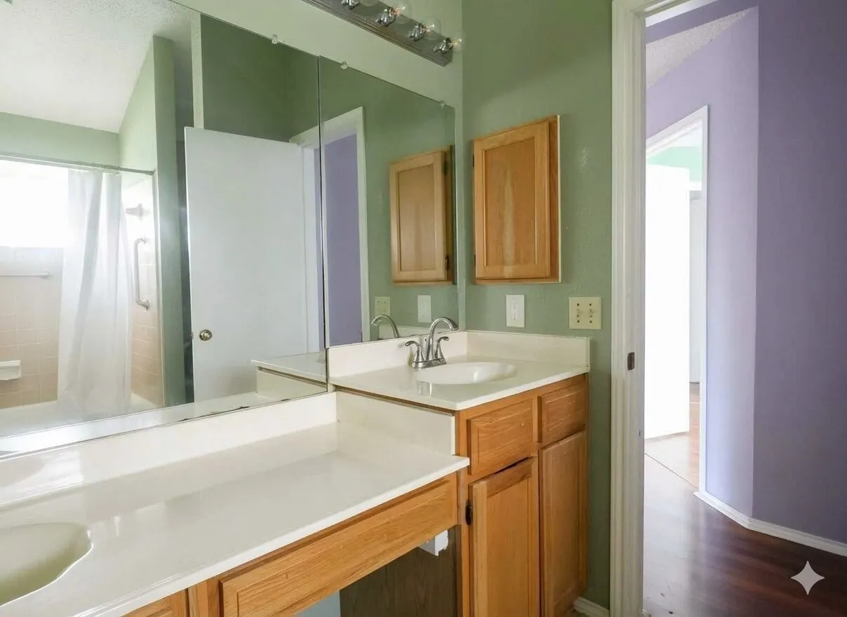 Double vanity with integrated sinks, light wood-finish cabinetry, and a large wall-mounted mirror