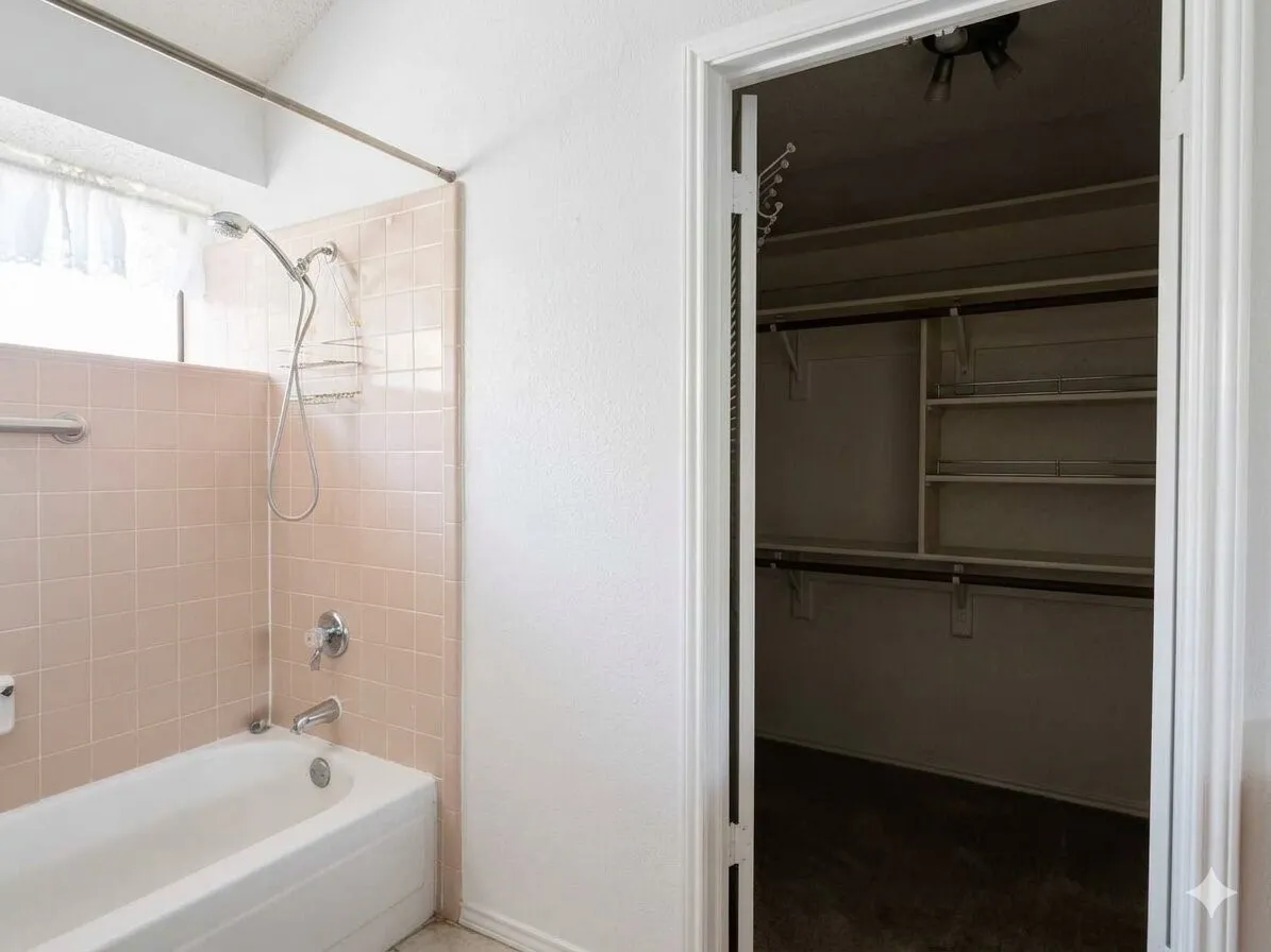 Bathroom featuring a tub/shower combination with tile surround and an adjacent closet with built-in shelving