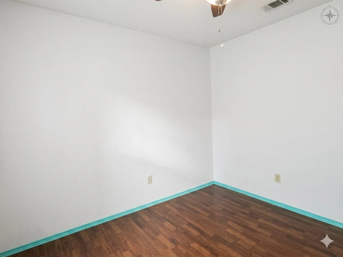 White walls featuring wood-finish flooring, a ceiling fan, and light blue trim