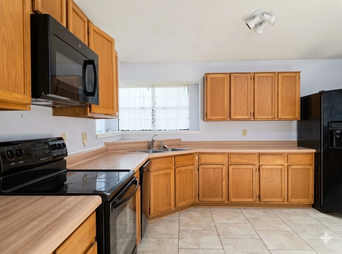Kitchen featuring wood-finish cabinetry, black appliances, a corner sink, and tile flooring