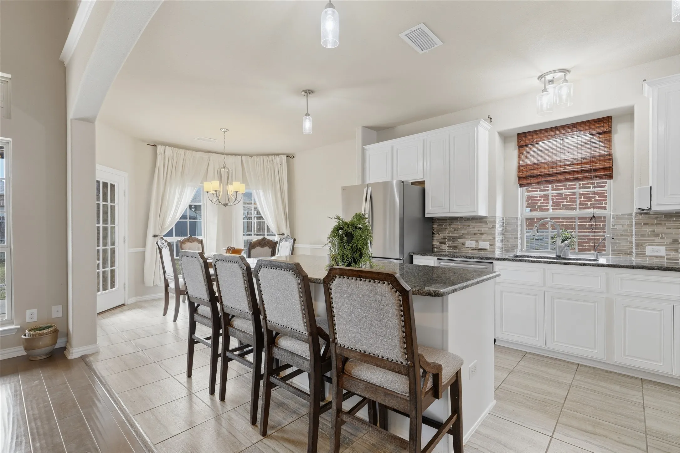 Kitchen featuring granite countertops, white cabinetry, stainless steel appliances, and a tile backsplash