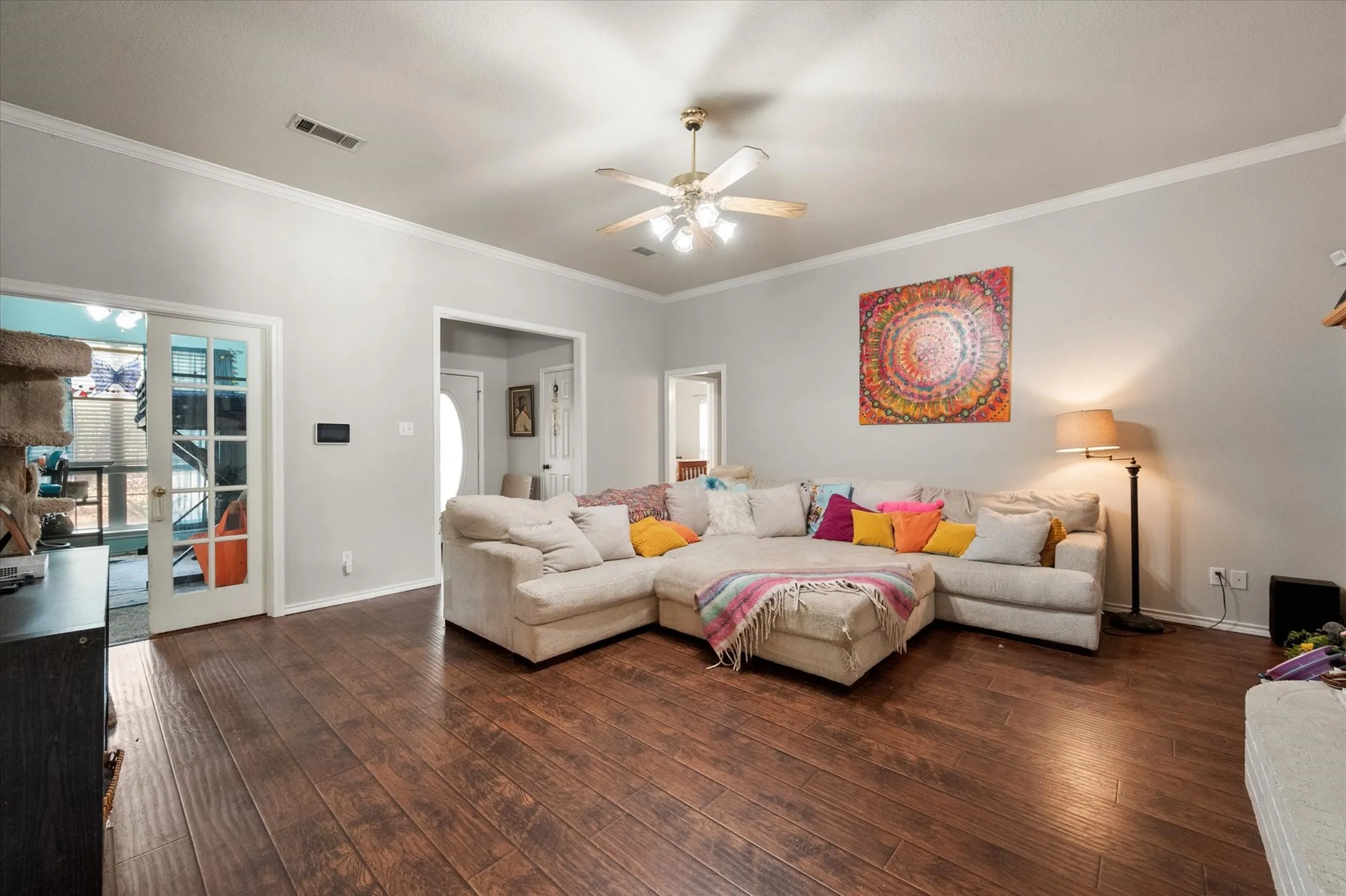 Wood-finish flooring, crown molding, ceiling fan with light fixture, and double glass-paned doors