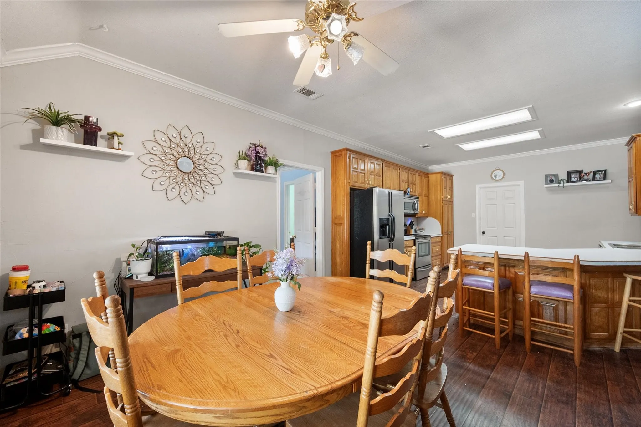 Hardwood-finish flooring, crown molding, a built-in kitchen island, recessed lighting, and wooden cabinetry