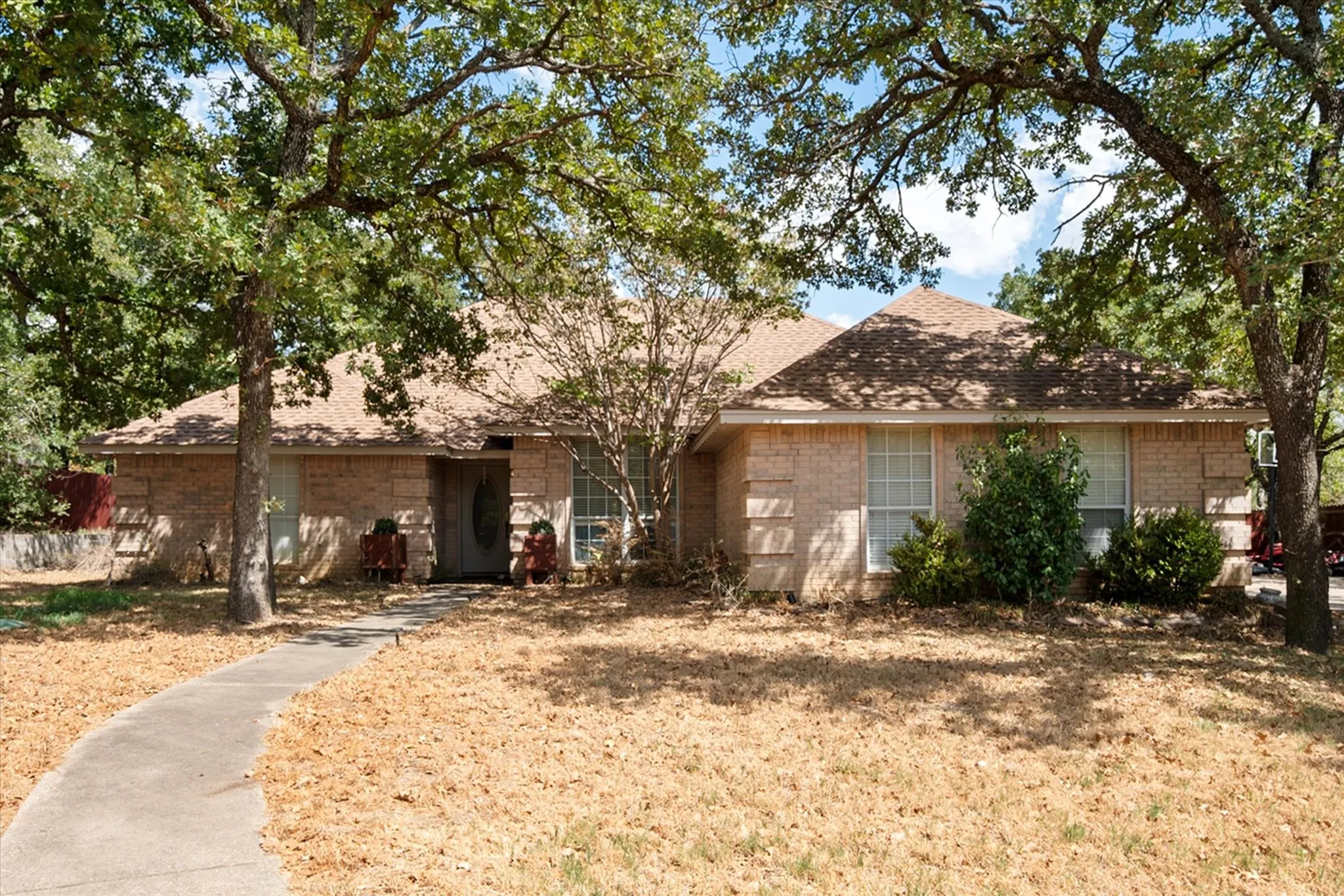 Brick exterior with a gabled roof and mature trees providing shade
