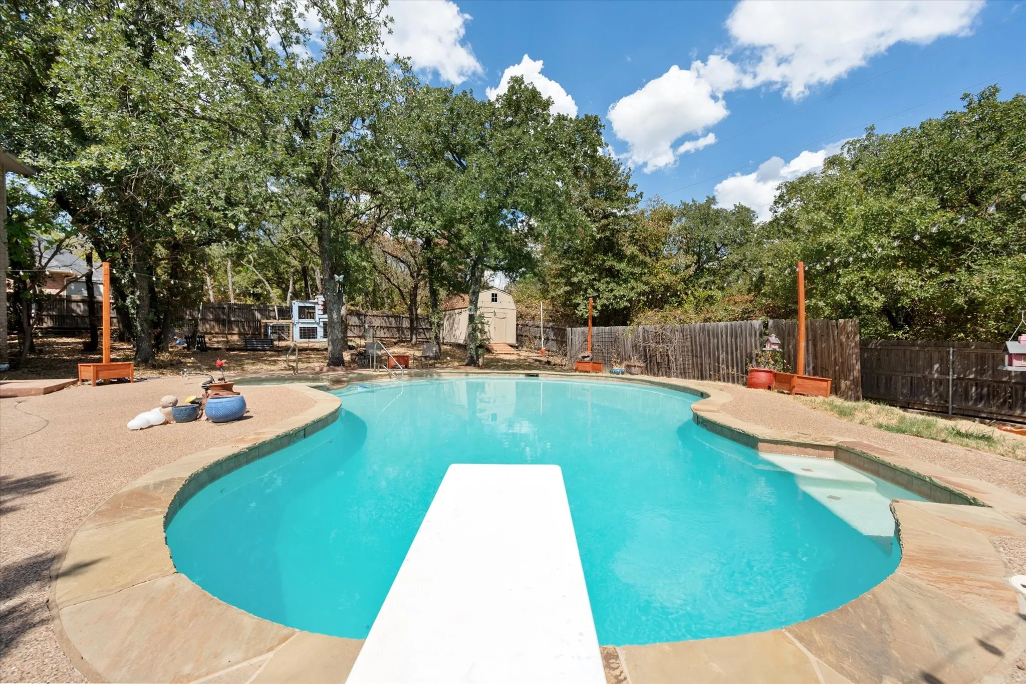 Freeform swimming pool with a diving board, integrated steps, and flagstone coping