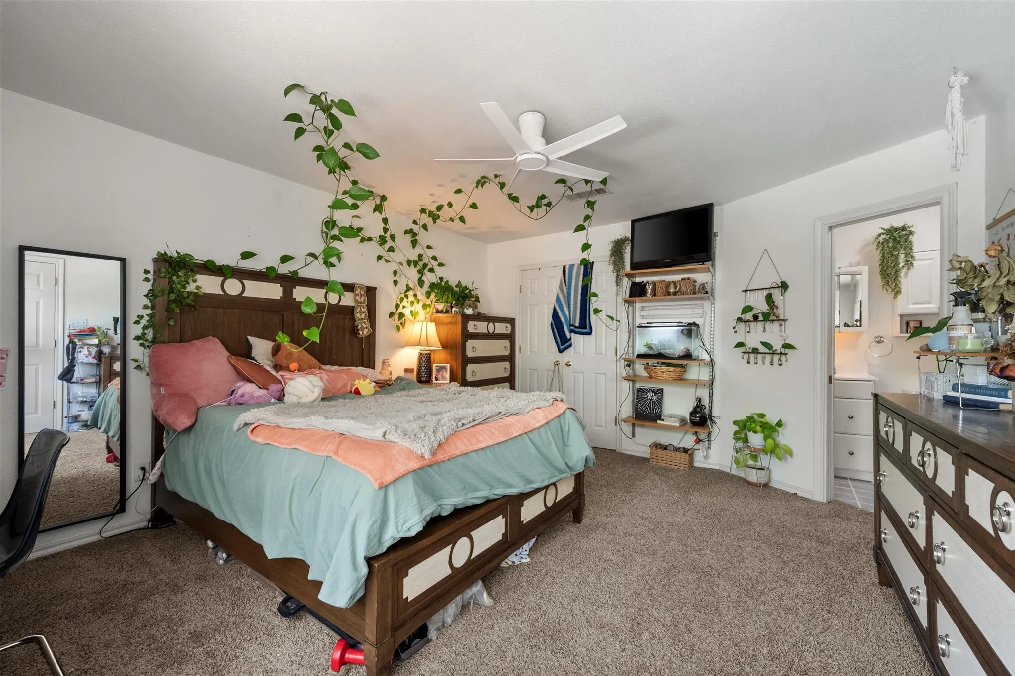 Carpeted bedroom with a ceiling fan, white walls, and a wood-finish bed frame