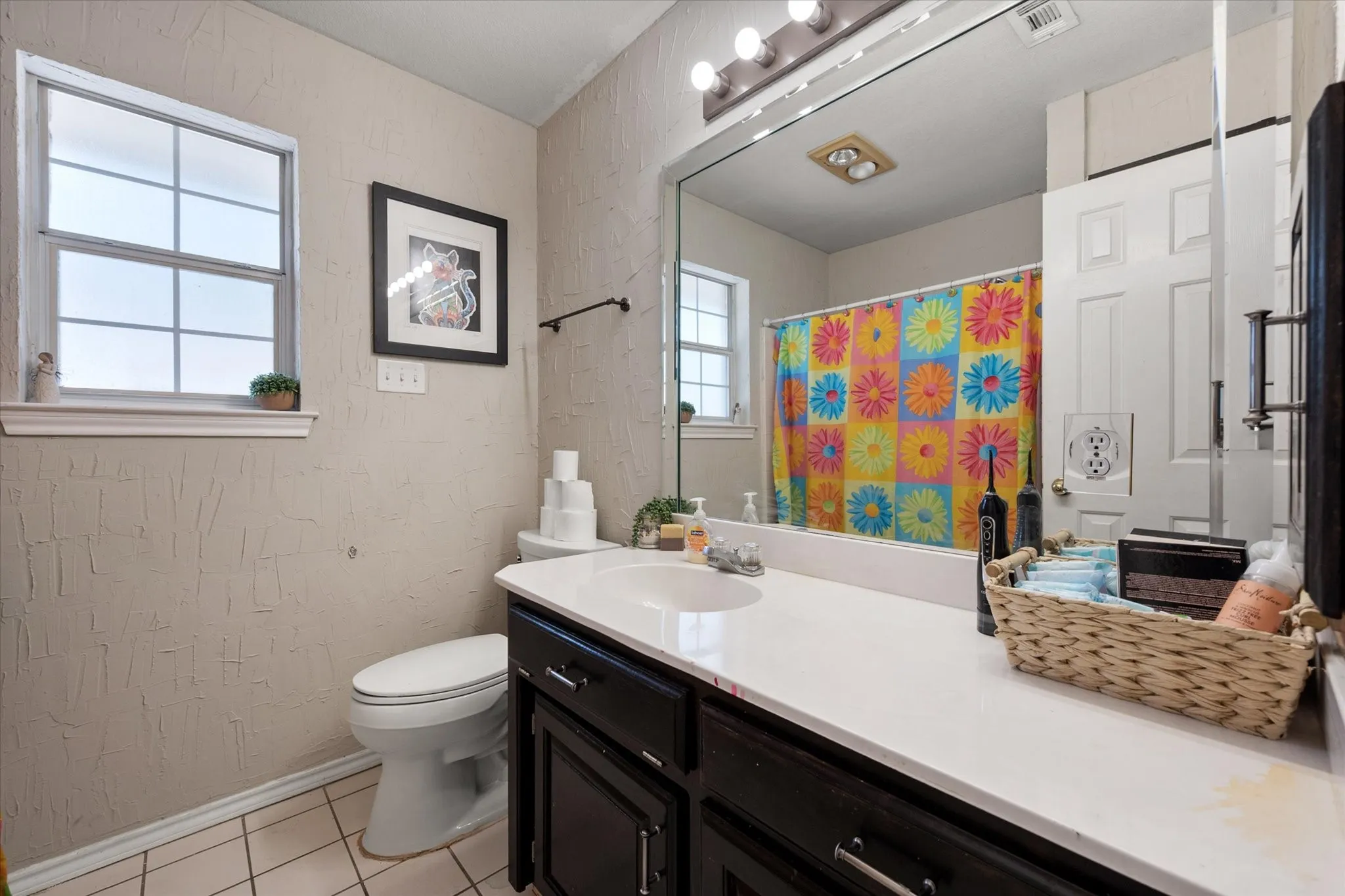 Vanity with integrated sink, expansive mirror, and dark wood-finish cabinetry