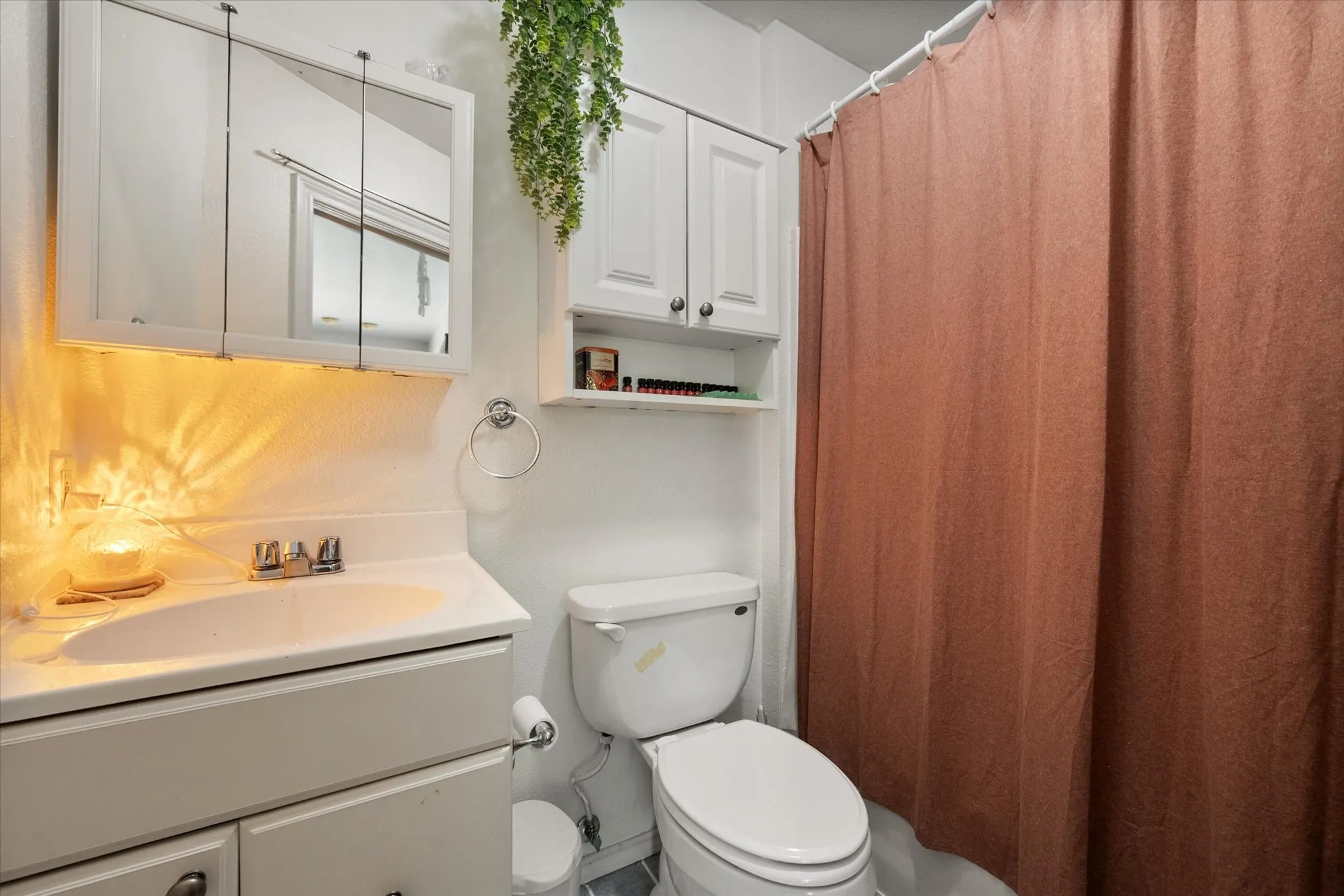 White vanity with integrated sink, chrome faucet, and mirrored medicine cabinet