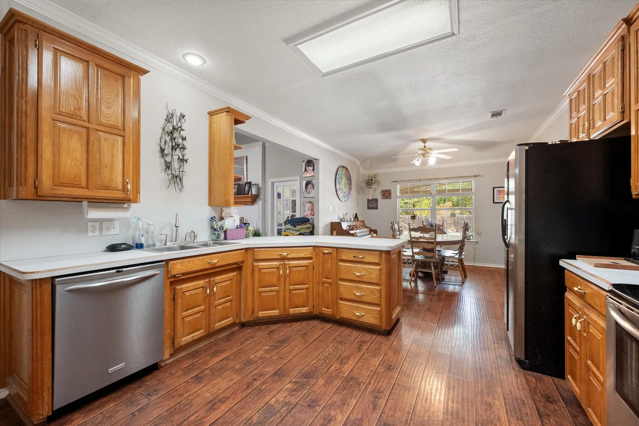 Kitchen featuring wood-finish flooring, wood cabinetry, white countertops, and a stainless-steel dishwasher