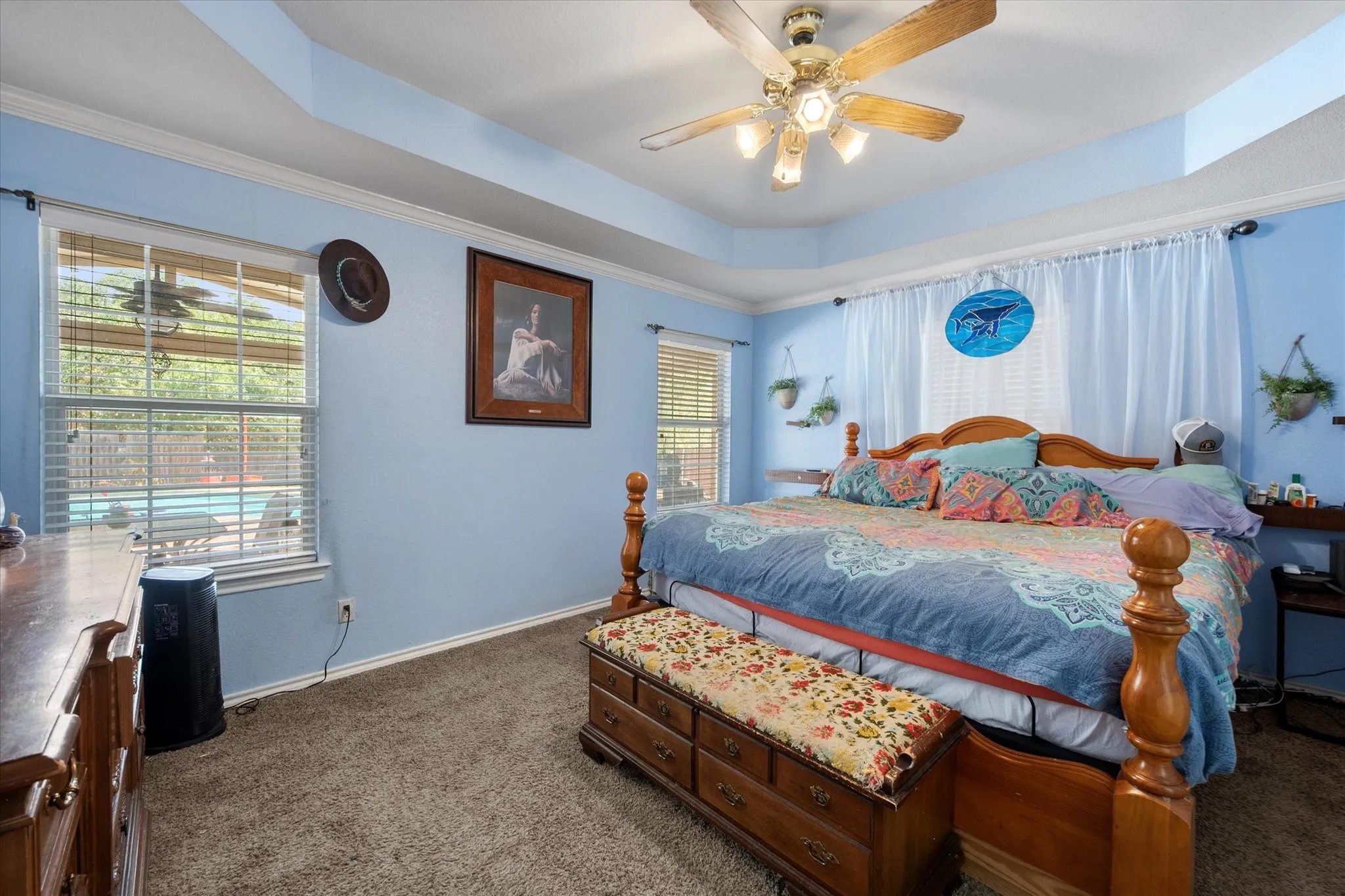Tray ceiling with crown molding, carpeted flooring, and a ceiling fan with light fixture