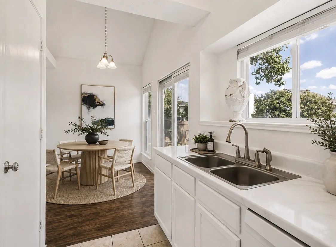 Kitchen featuring white cabinetry, a dual basin stainless steel sink with a gooseneck faucet, and light-toned countertops