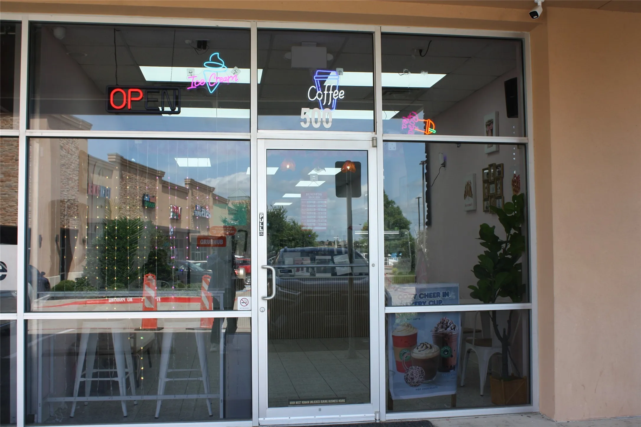 Aluminum-framed storefront with large glass panels, a single entry door, and exterior sconce lighting