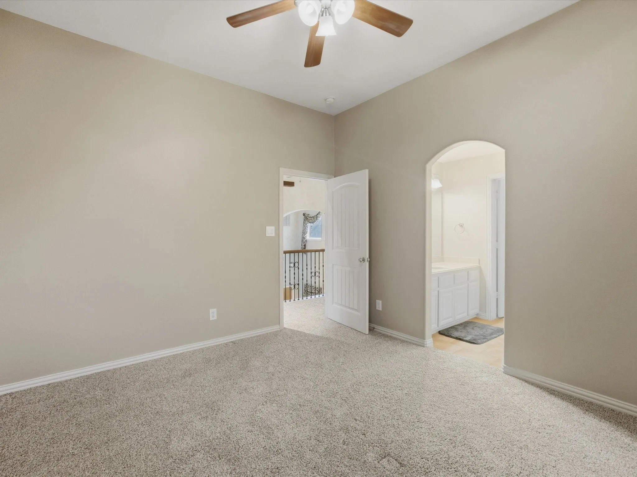 Vaulted ceiling with ceiling fan, light-toned carpeting, white trim, and interior doors