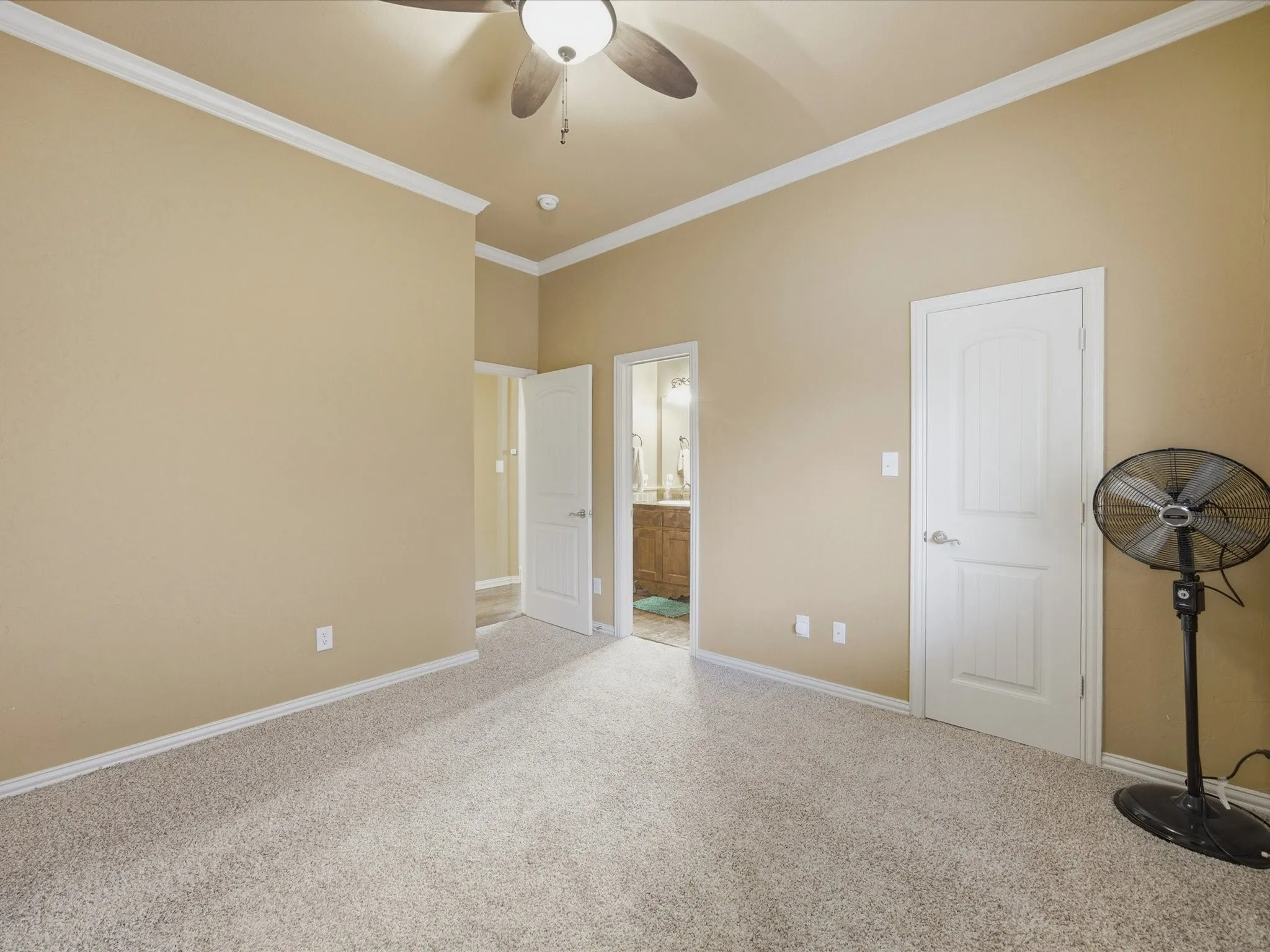 Vaulted ceiling with crown molding, ceiling fan, and carpeted flooring