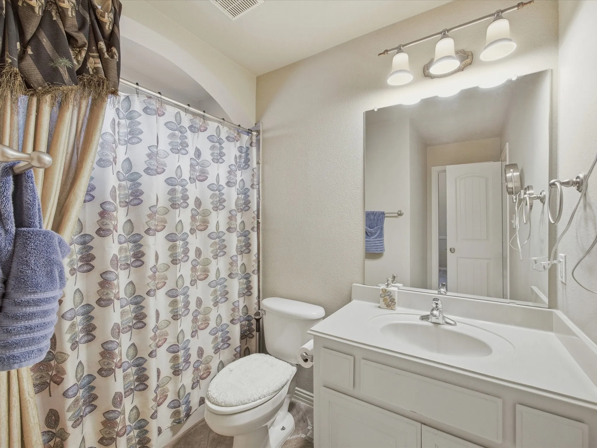 White vanity with a single basin, brushed nickel faucet, and a large wall-mounted mirror