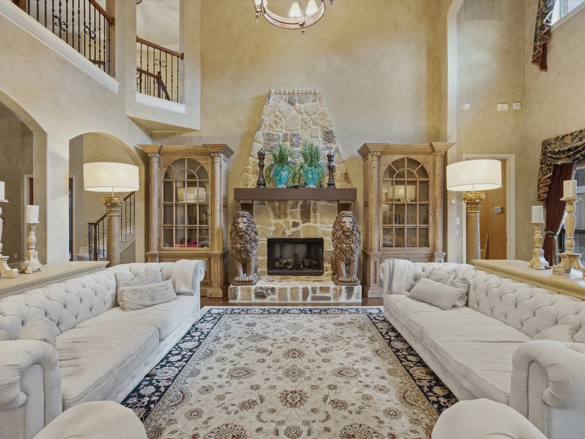 Two-story living area with a stone fireplace, wood mantel, and arched doorways