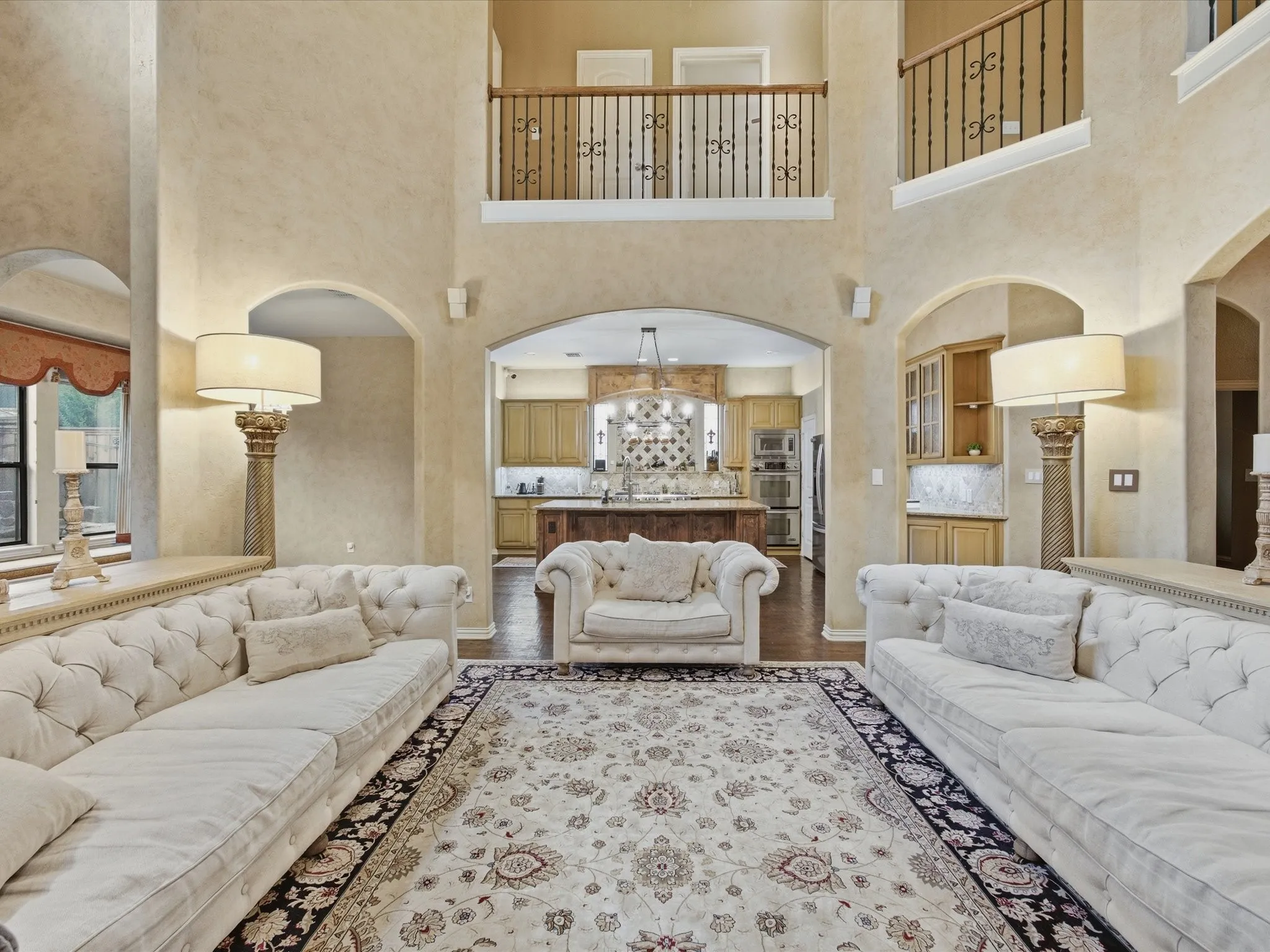 Soaring ceilings with upper-level balconies, arched doorways, and hardwood flooring