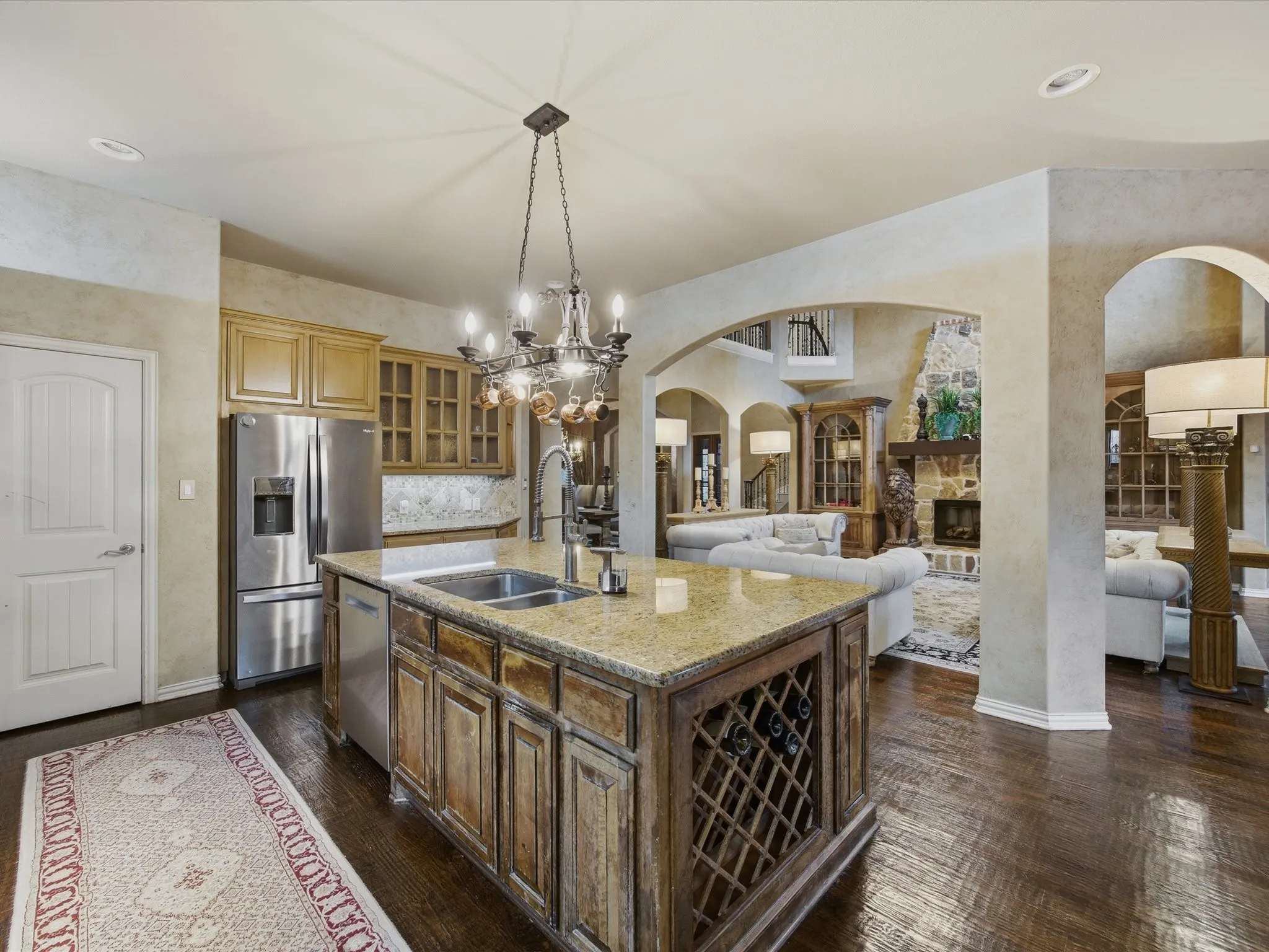 Gourmet kitchen island with an integrated wine rack, double basin sink, and granite countertop